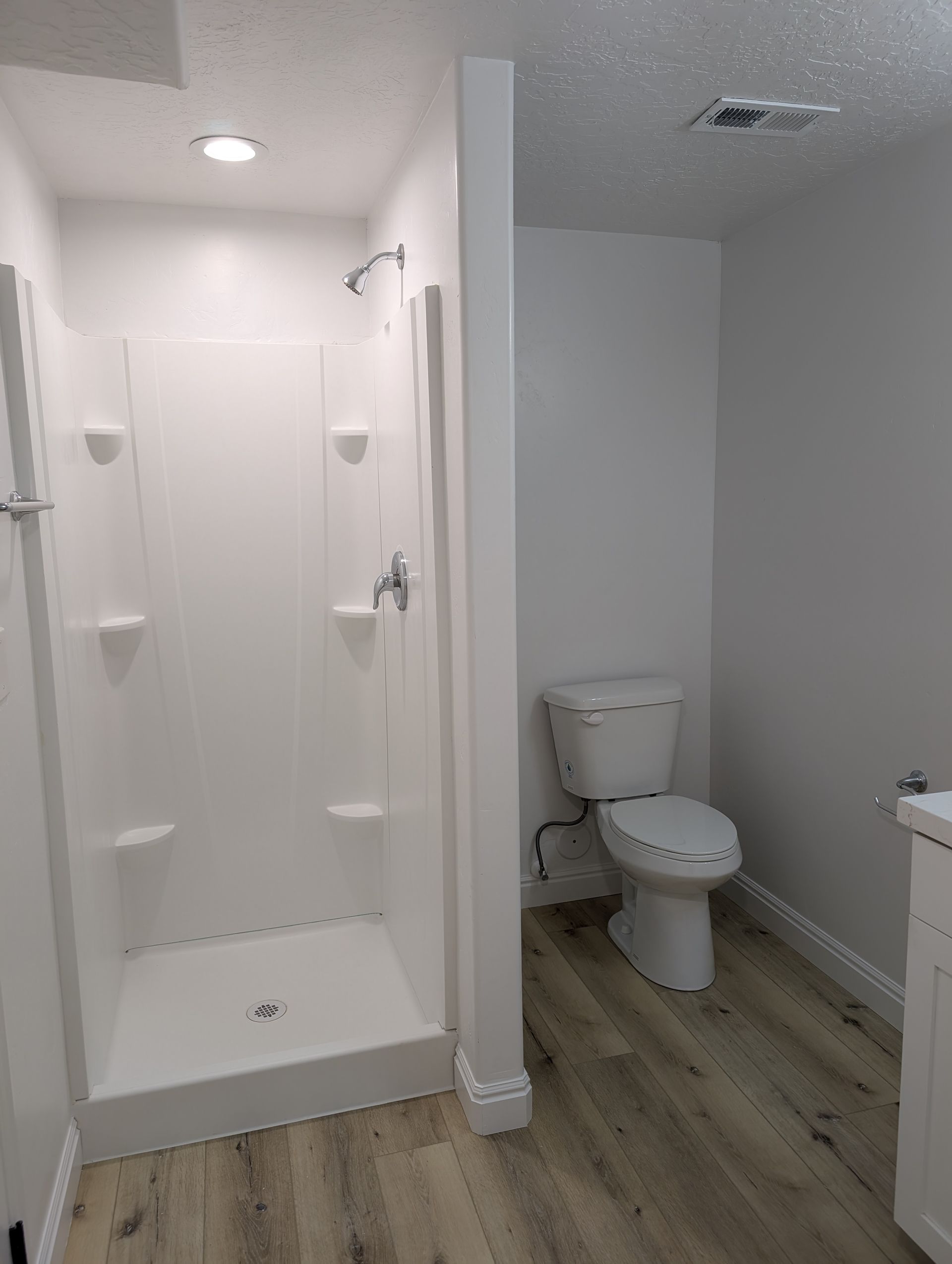 A bathroom with a toilet , shower and sink.