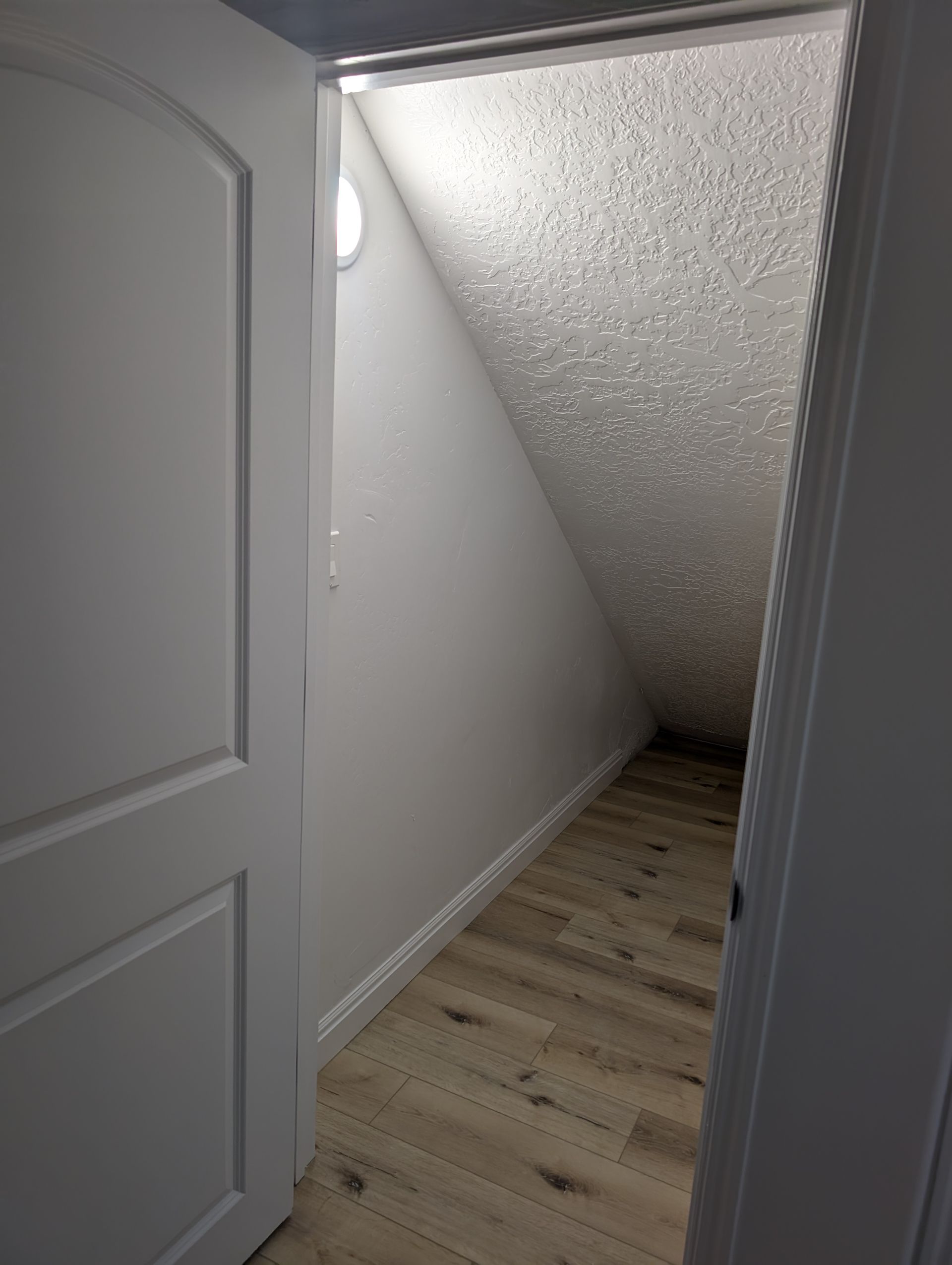 A hallway with a door open and a ceiling that is very steep.