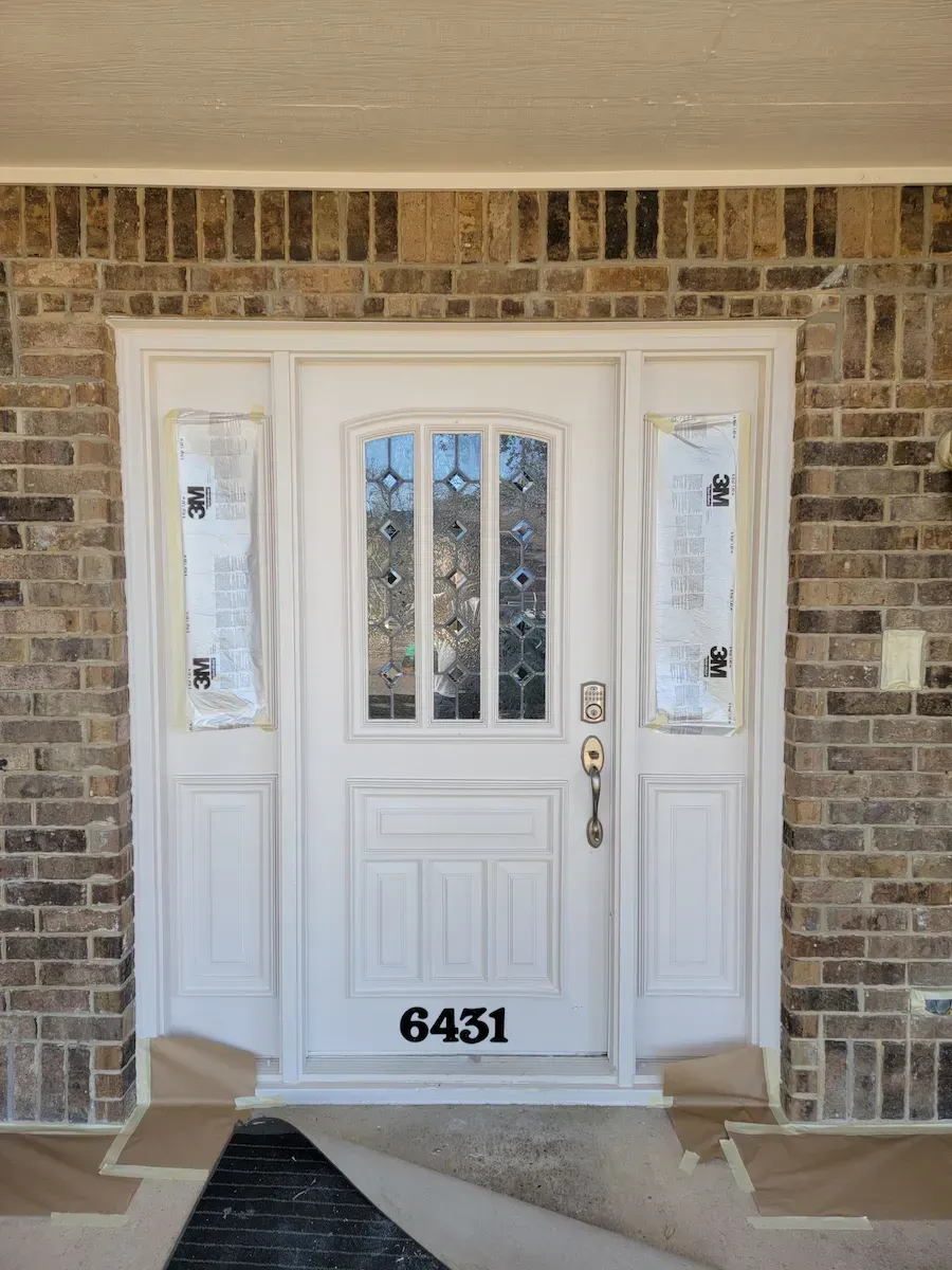 A white front door with a brick wall
