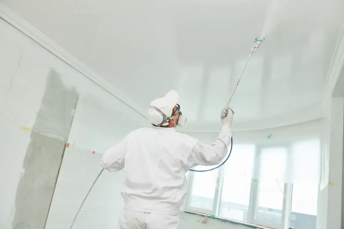 An interior painter paiting the ceiling white