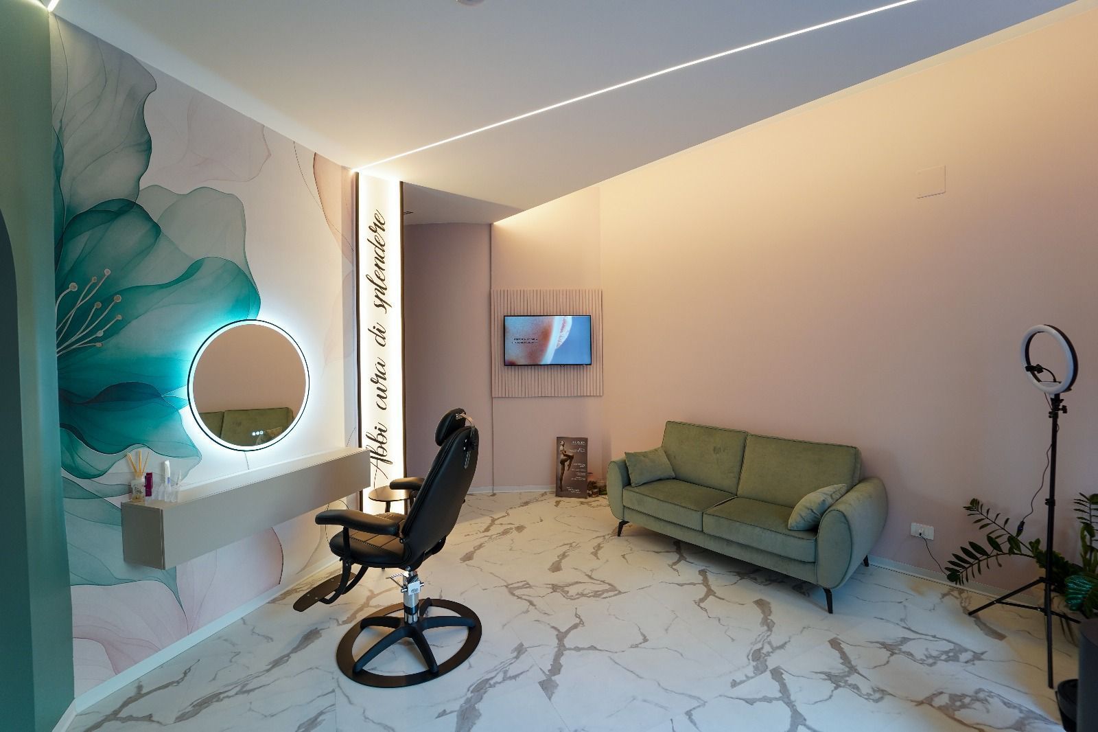 Interno di un salone di bellezza con pareti verdi e rosa, pavimento in marmo, sedia, divano, specchio e luce ad anello.