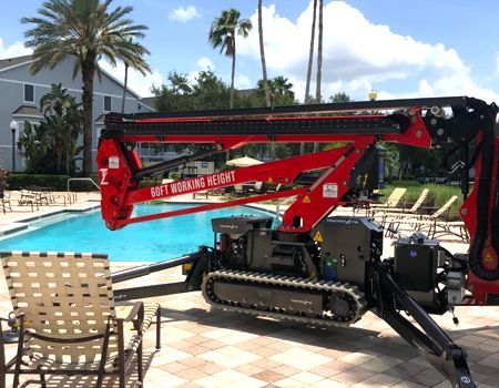 Red spider lift near a pool, with outstretched arm, ready for work.