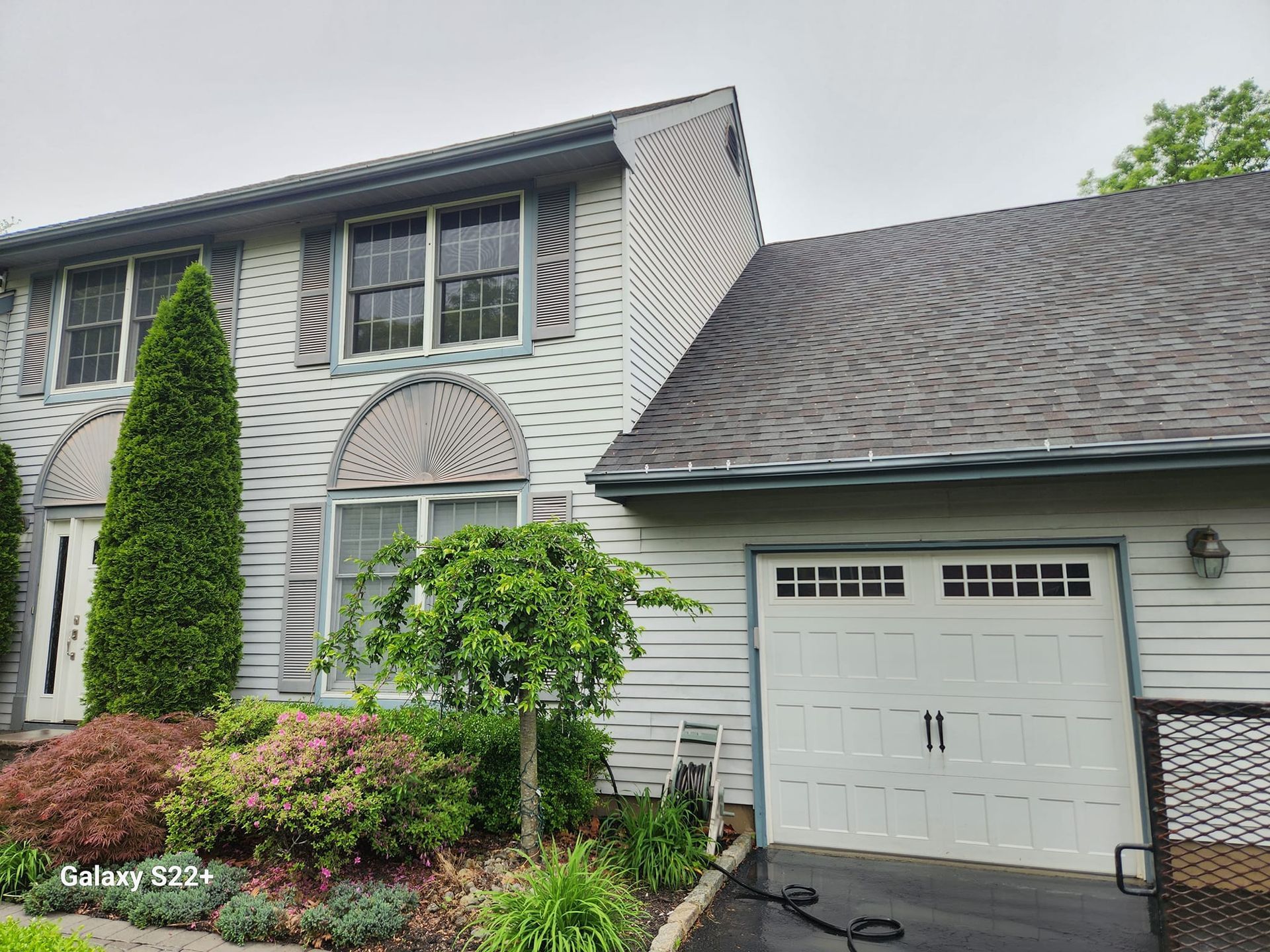 A white house with a black roof and a white garage door