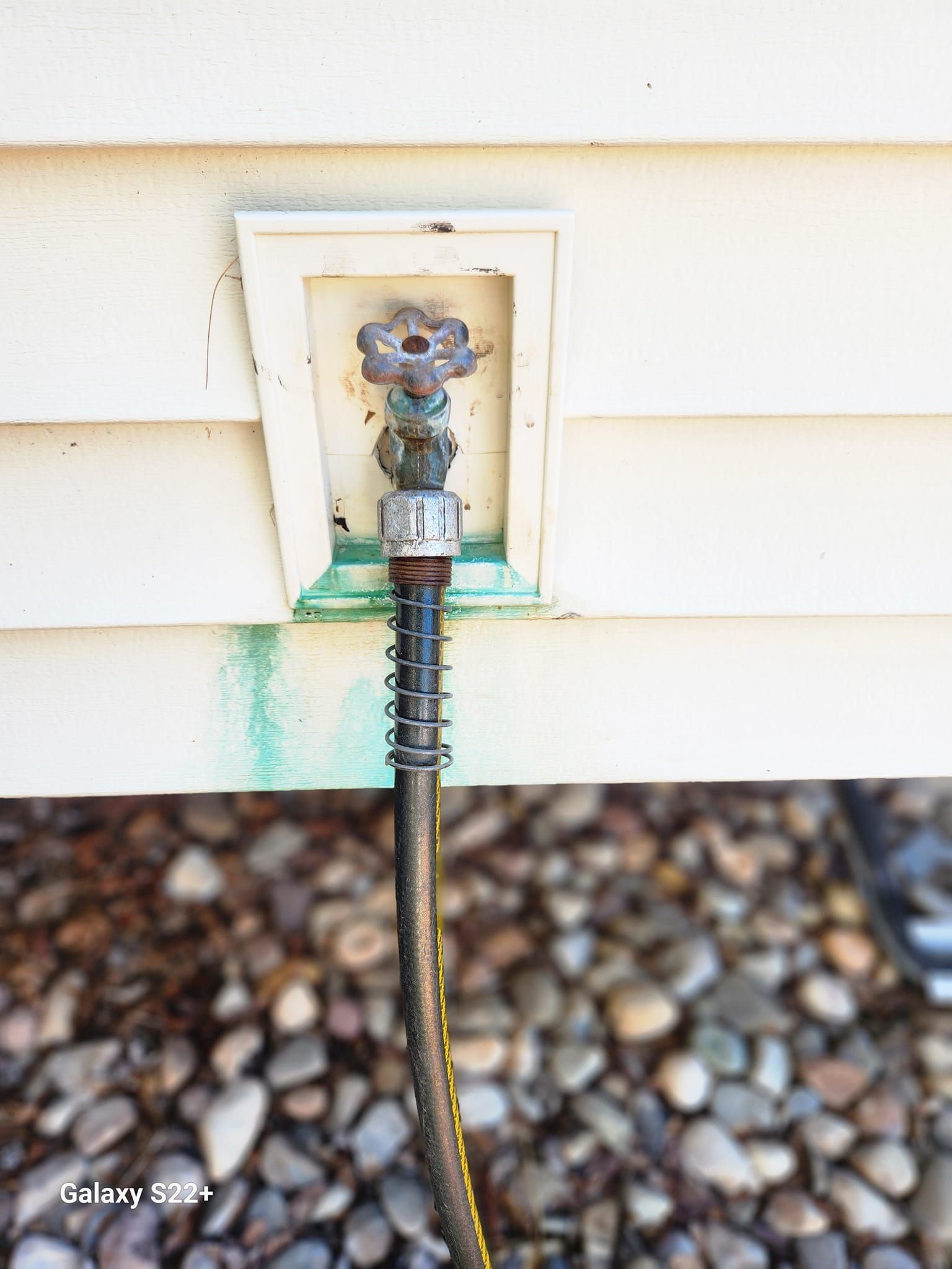 A hose is attached to the side of a dirty house.