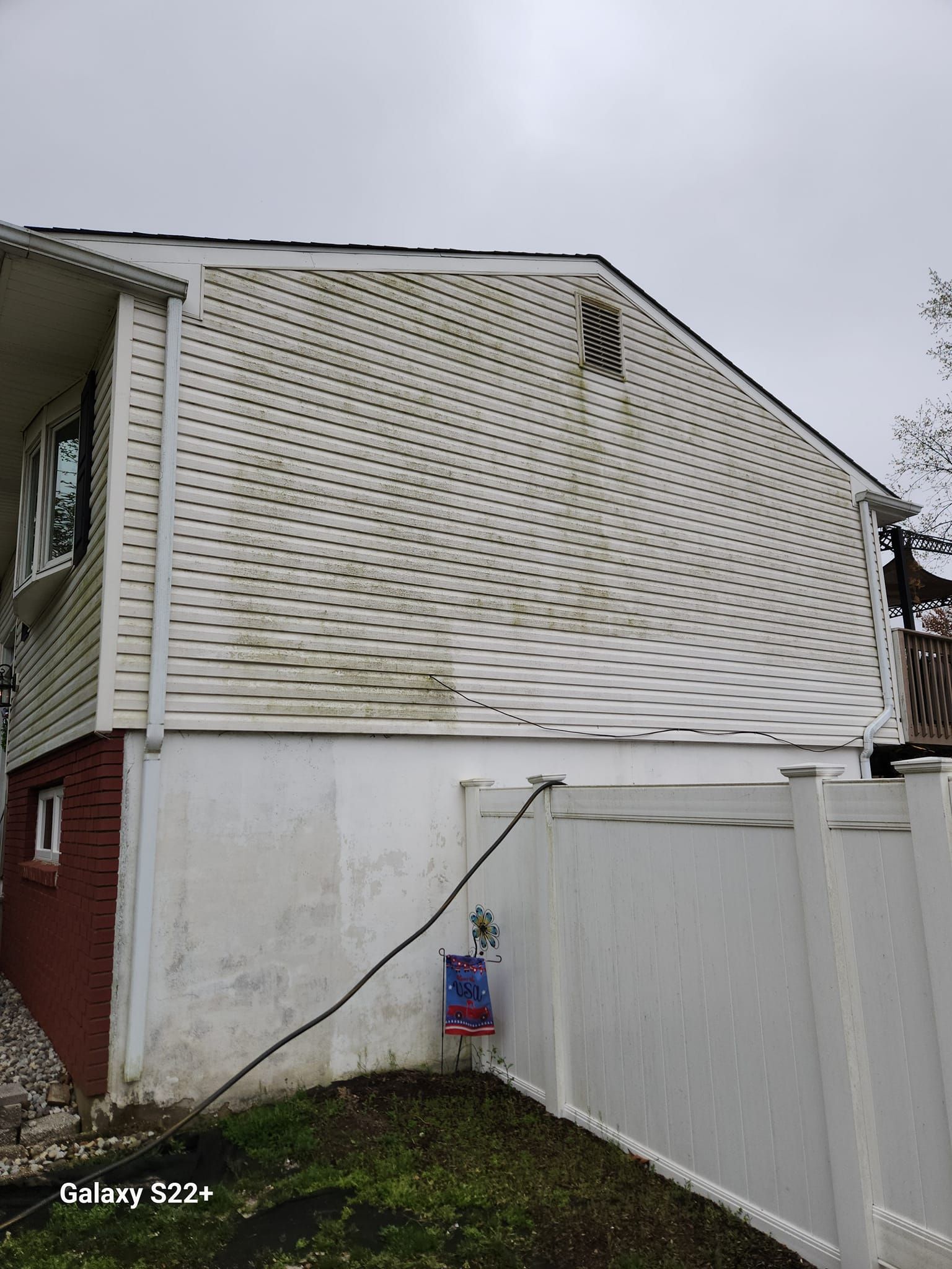 The back of a house with a white fence and a white roof.