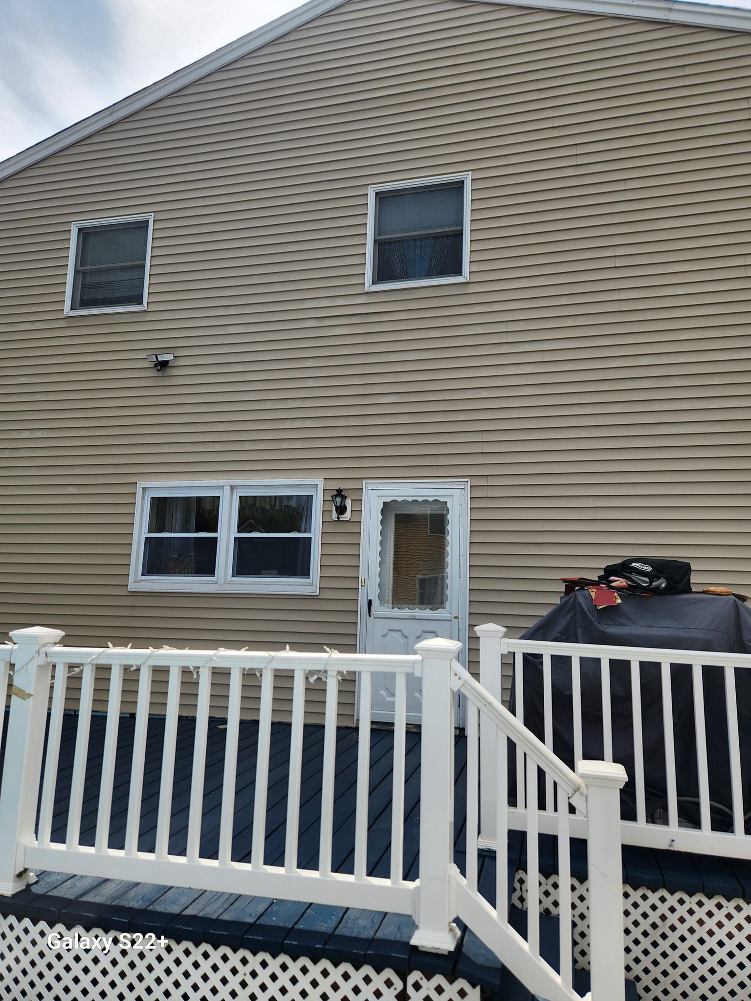 The back of a house with a white railing and stairs