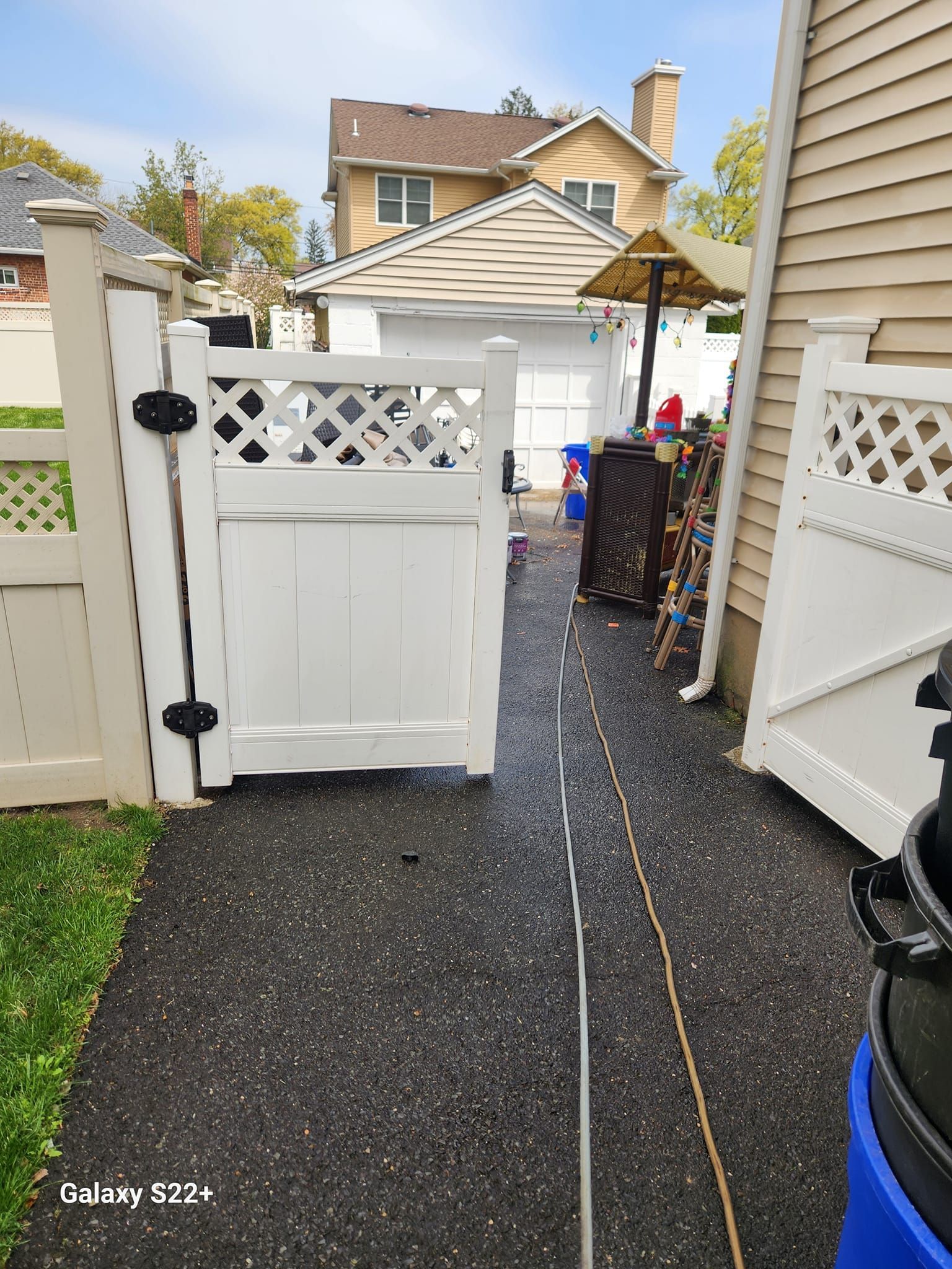 A white gate is sitting on a sidewalk next to a house.
