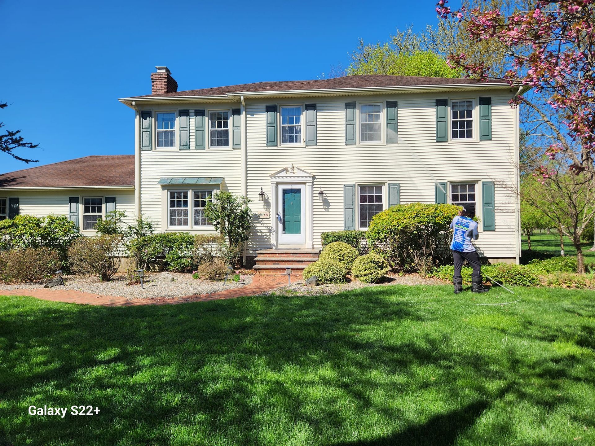 A woman is standing in front of a large white house.