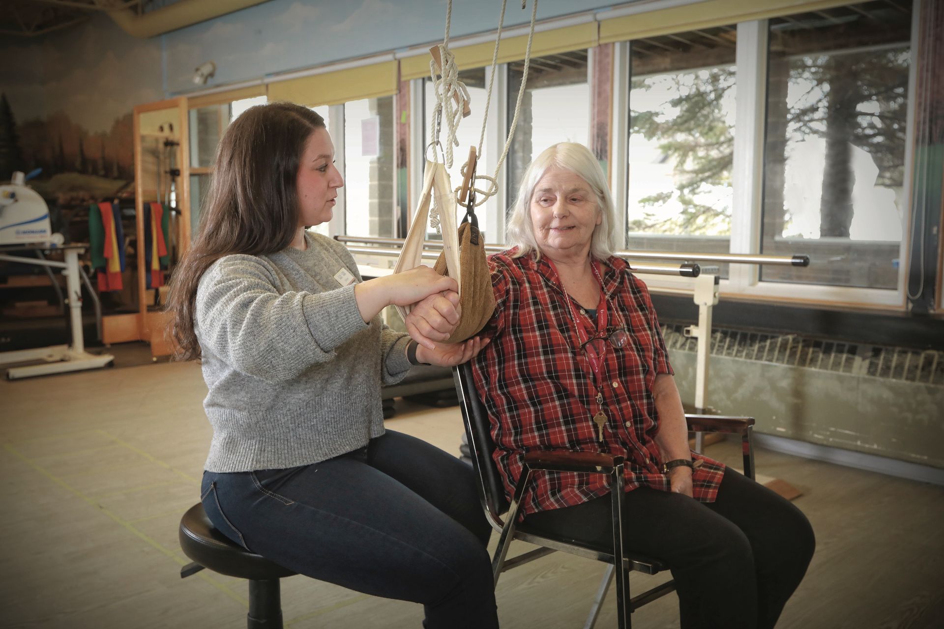A young woman is helping an older woman in a chair.