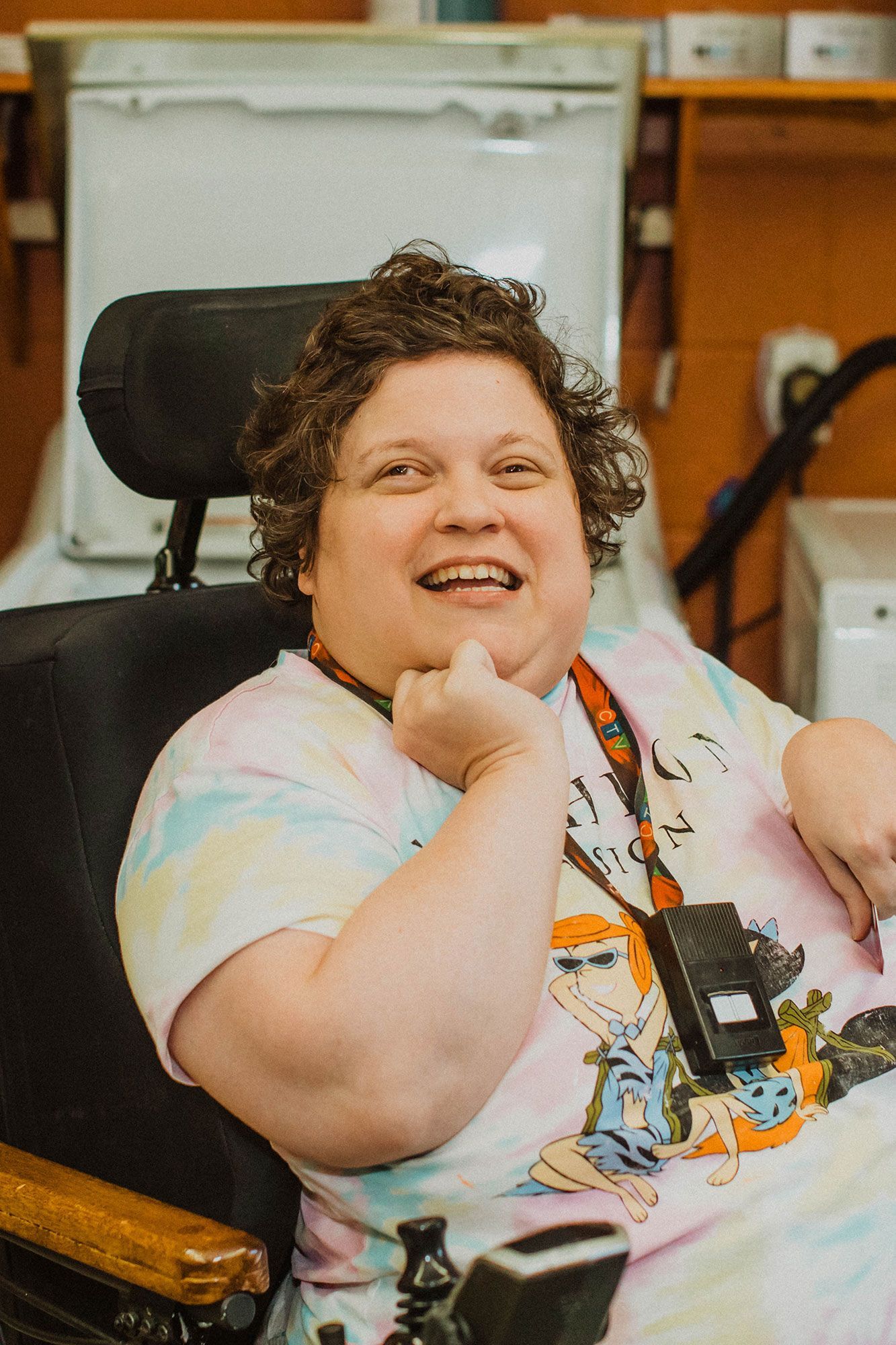 A woman is sitting in a wheelchair and smiling.