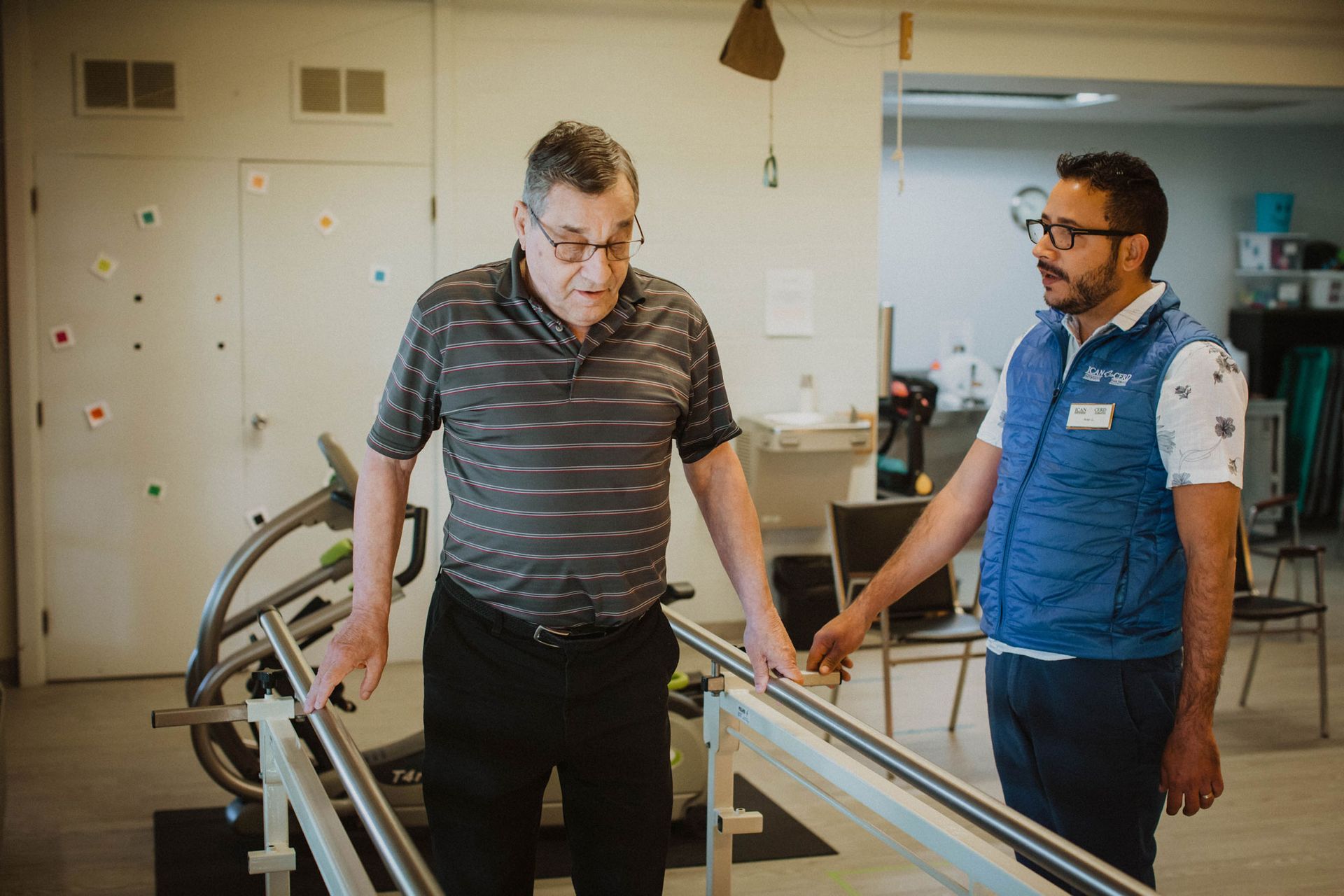 A man is walking on a treadmill with a physical therapist.
