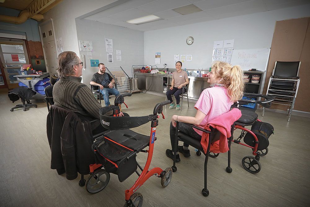 A group of people are sitting in a circle in a room with walkers.