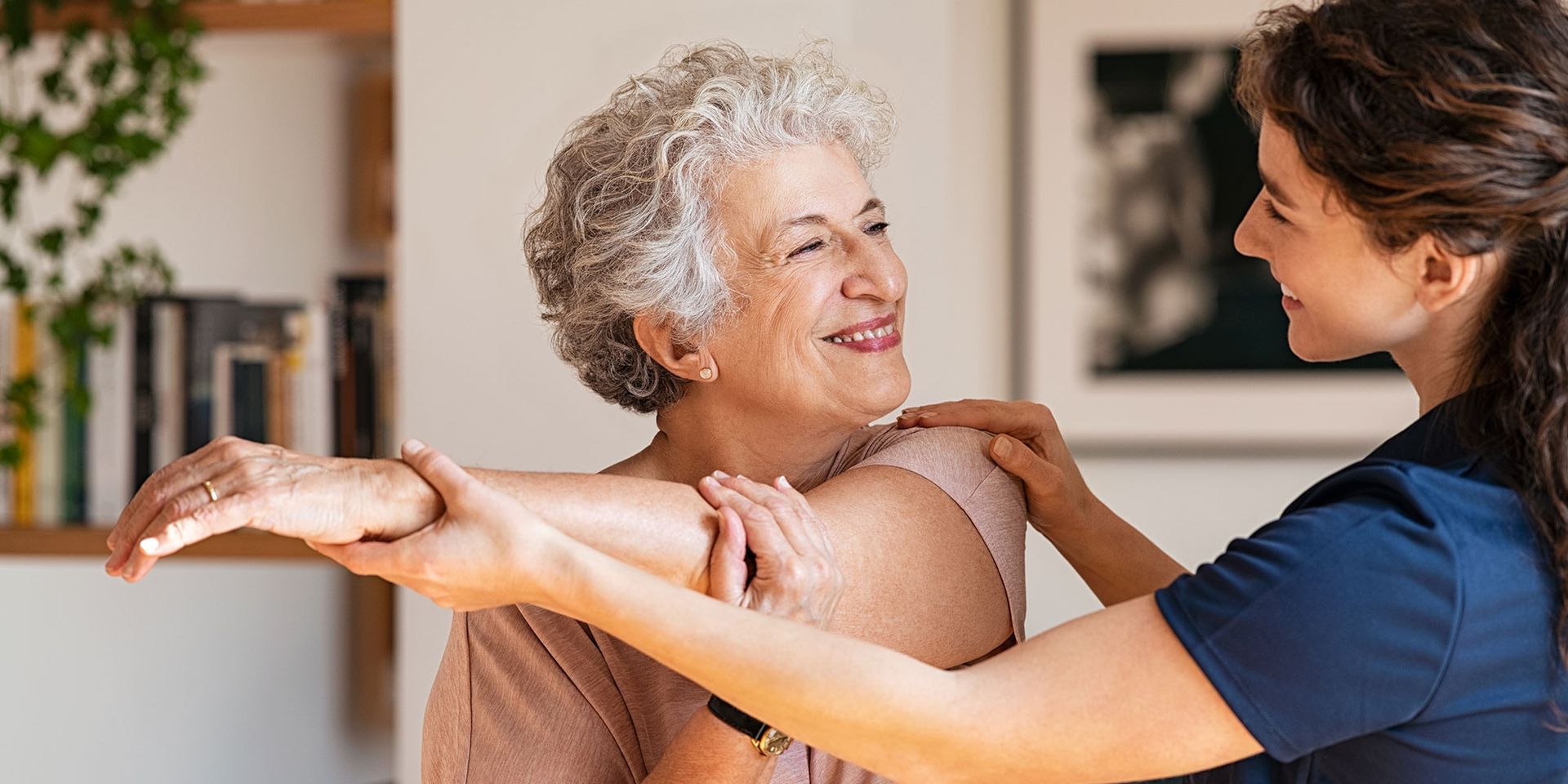 A nurse is helping an elderly woman stretch her arm.