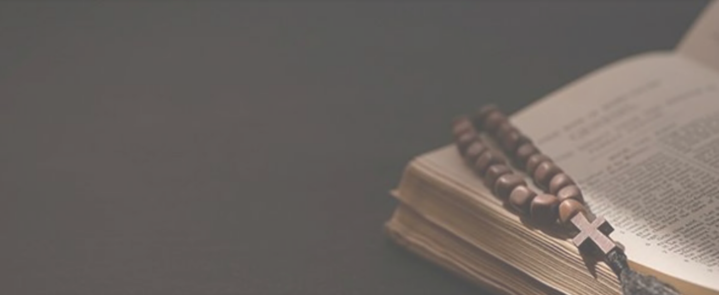 A rosary is sitting on top of an open bible.