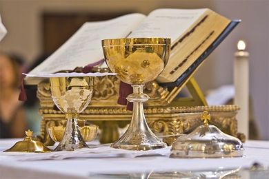 A table with a bible a chalice and a candle on it