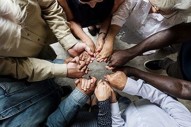 A group of people are sitting in a circle holding hands.
