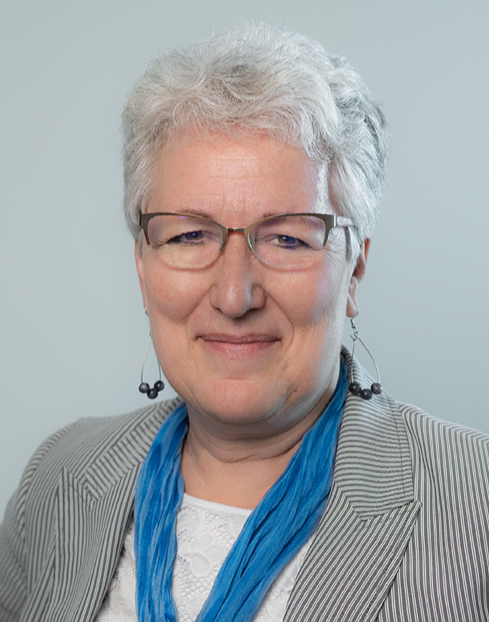 A woman with blonde hair and blue eyes is smiling for the camera