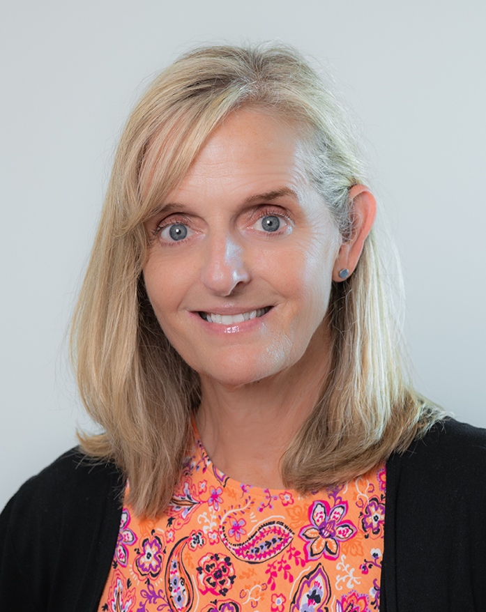 A woman with blonde hair and blue eyes is smiling for the camera