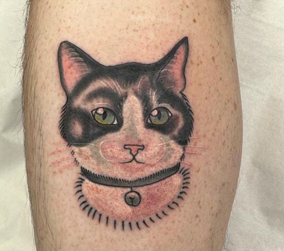A tattoo of a black and white cat wearing a collar