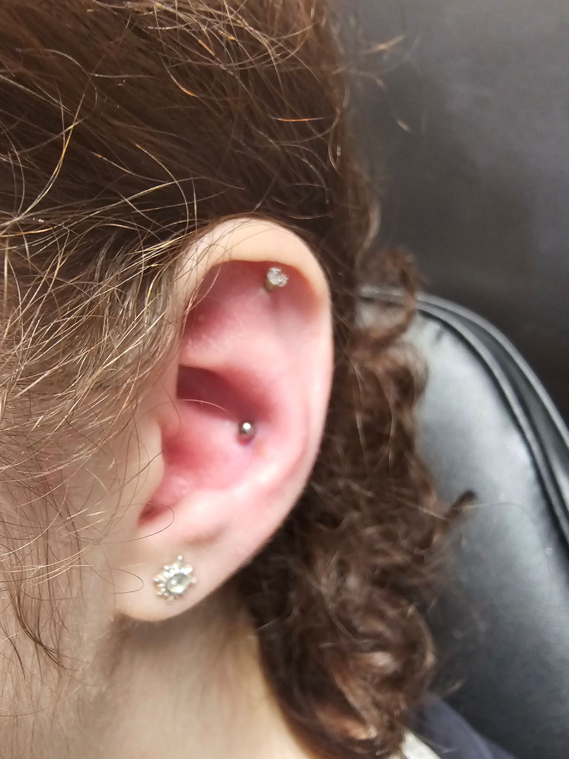 A close up of a woman 's ear with multiple piercings