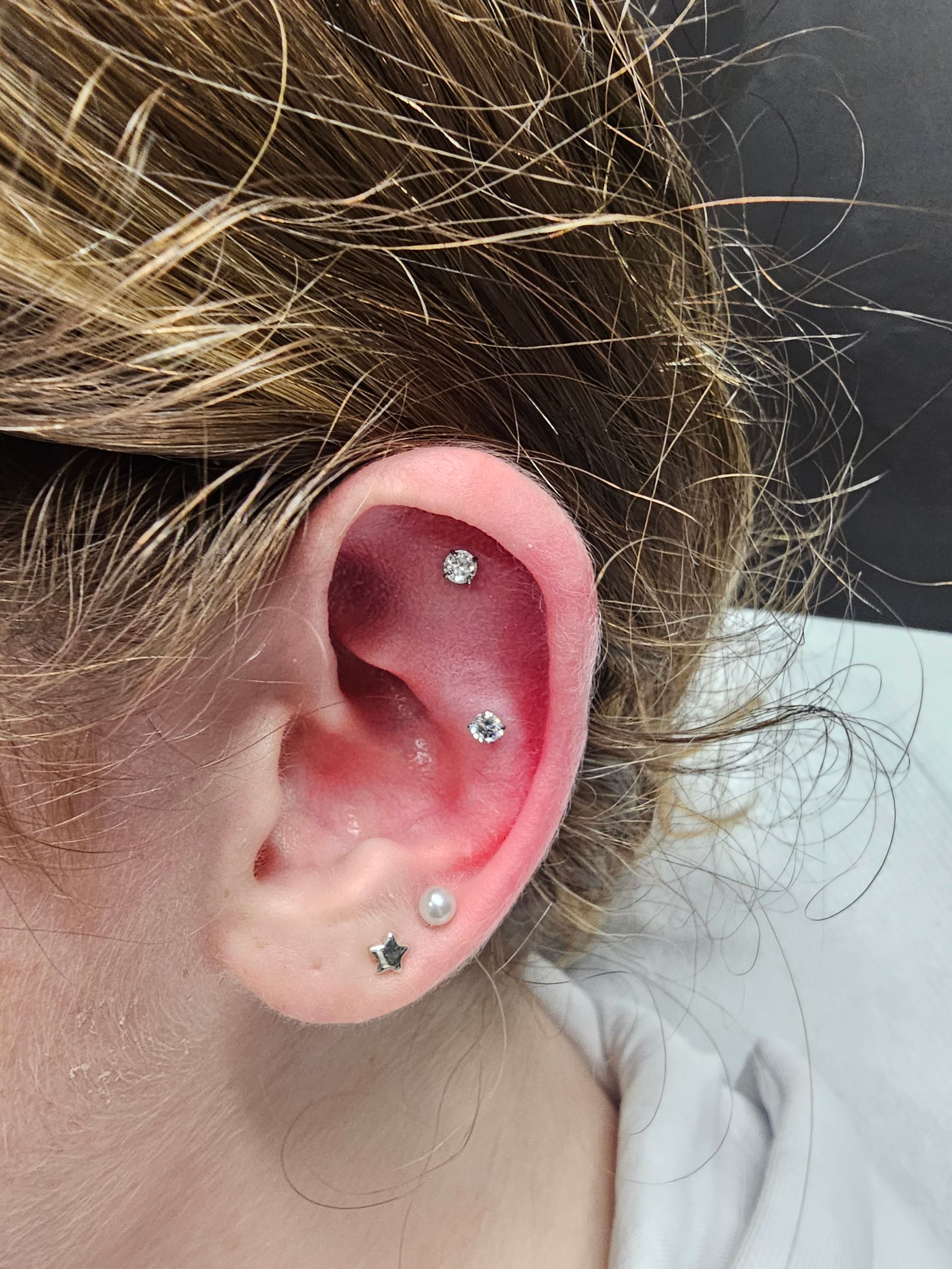 A close up of a woman 's ear with multiple piercings