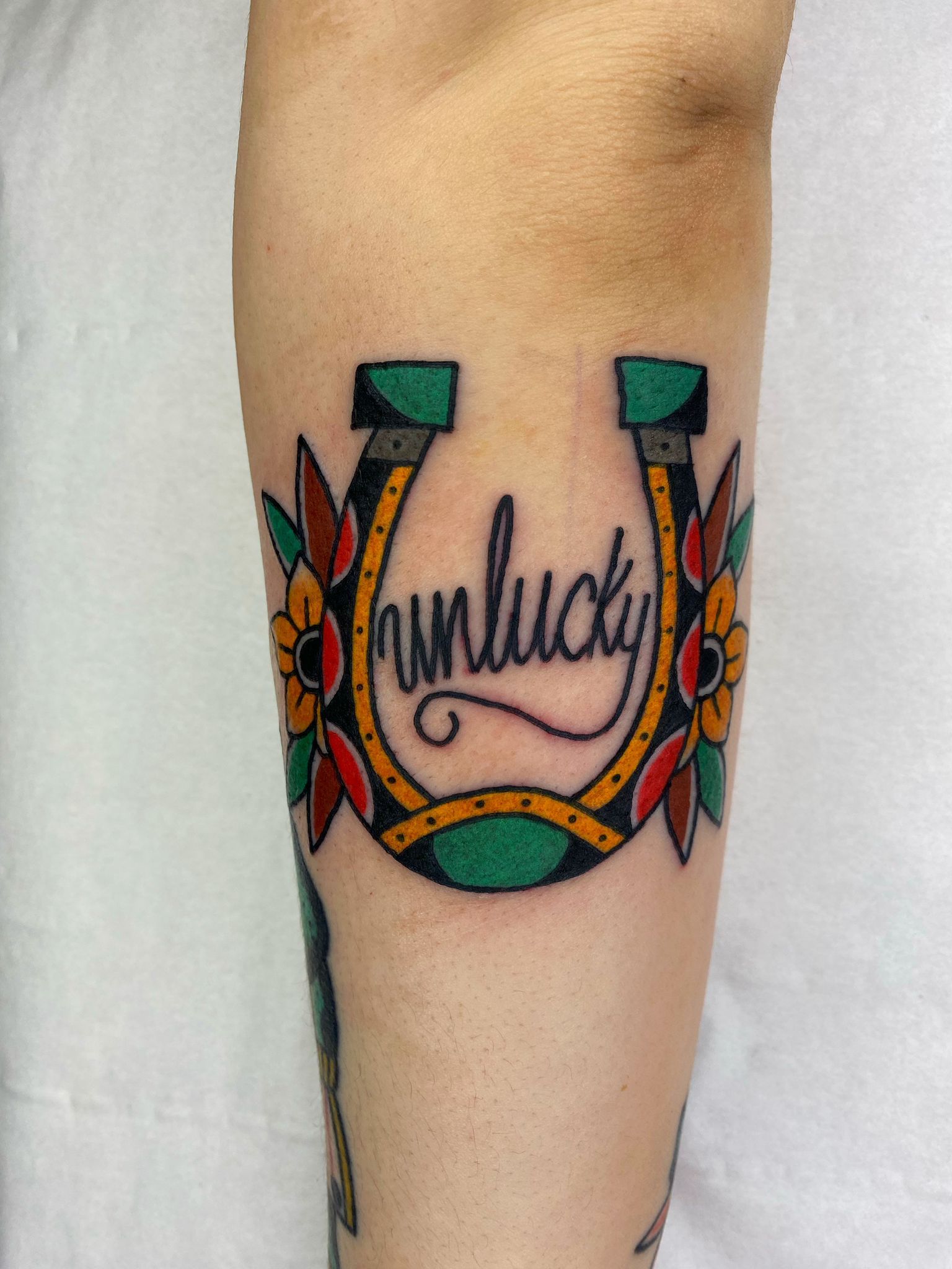 A tattoo of a horseshoe with the word runlucky on it