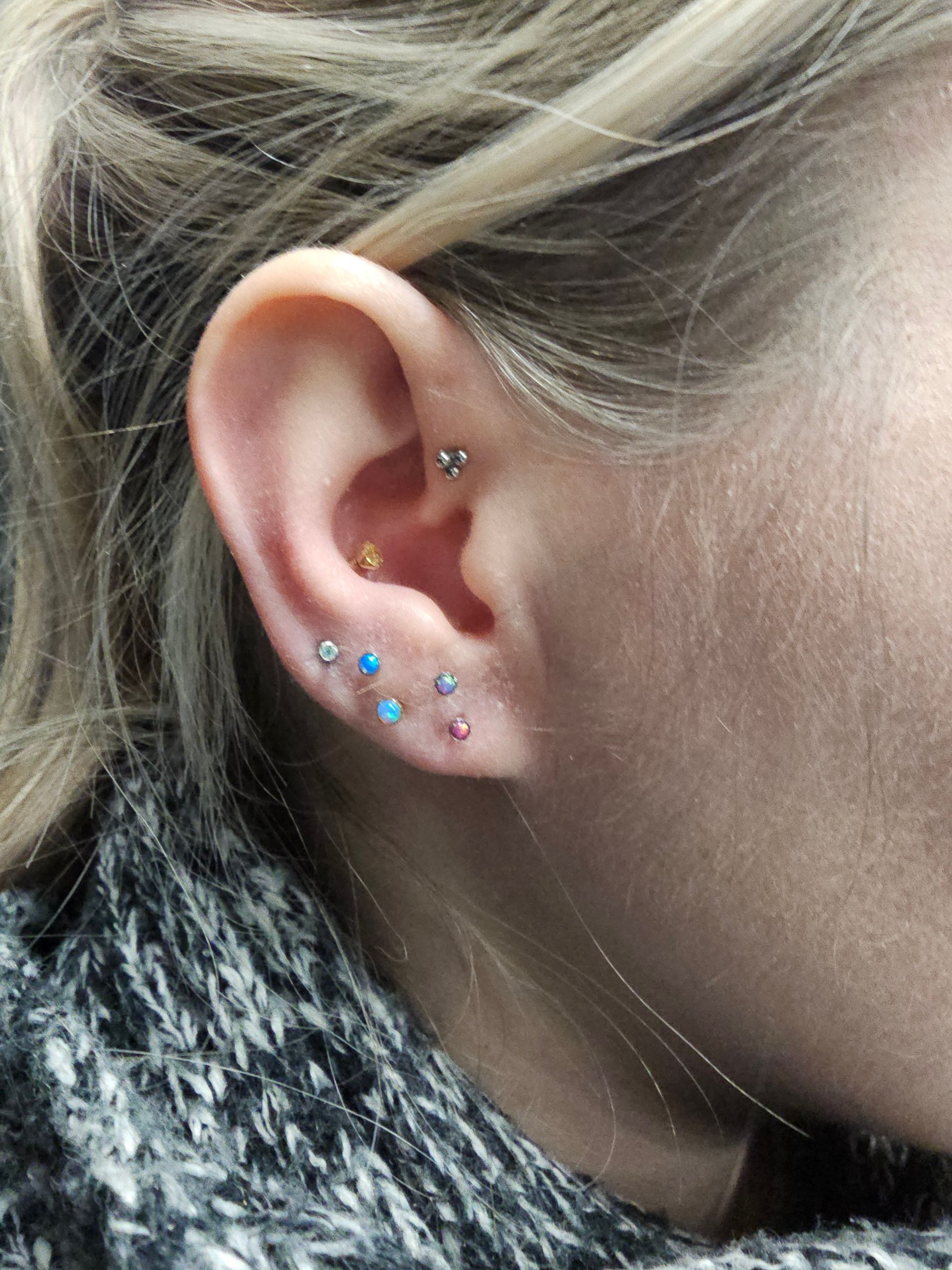 A close up of a woman 's ear with multiple piercings.