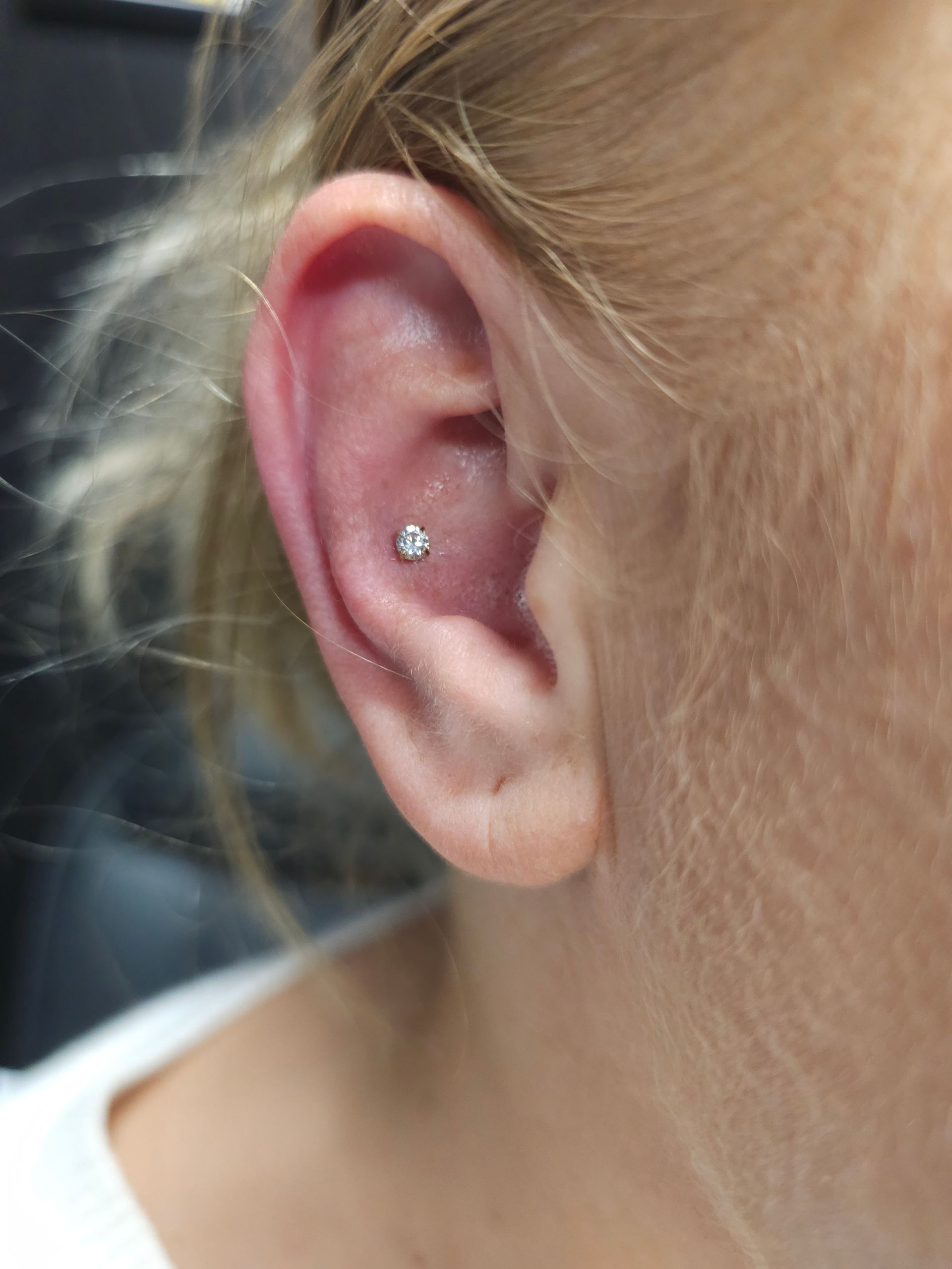 A close up of a woman 's ear with a piercing.