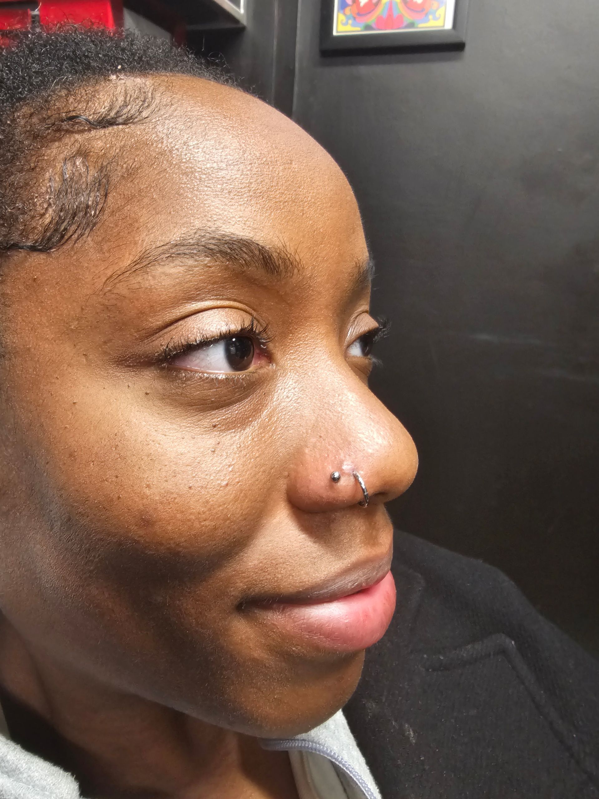 A close up of a woman 's face with a nose ring.