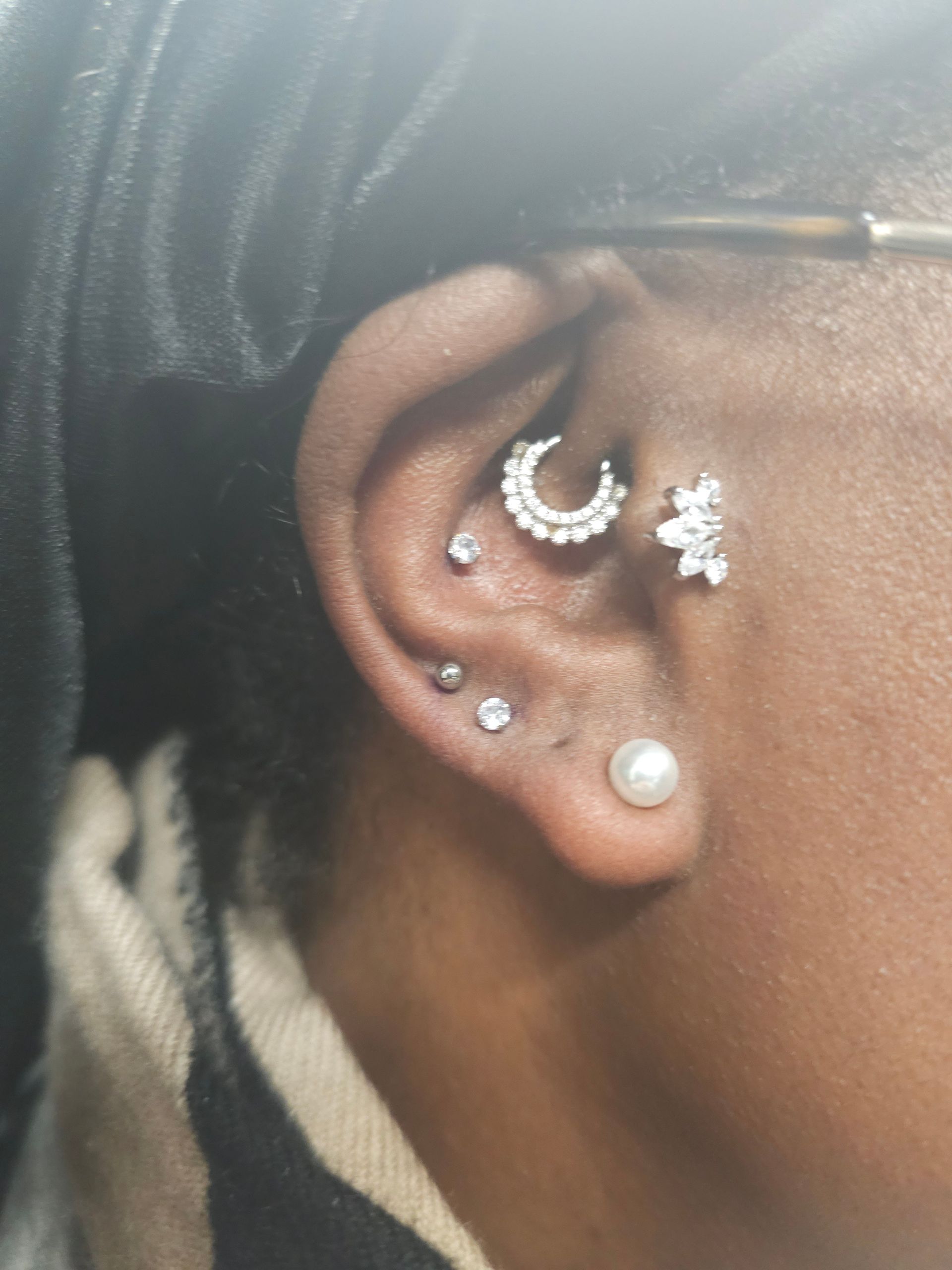 A close up of a woman 's ear with multiple piercings.