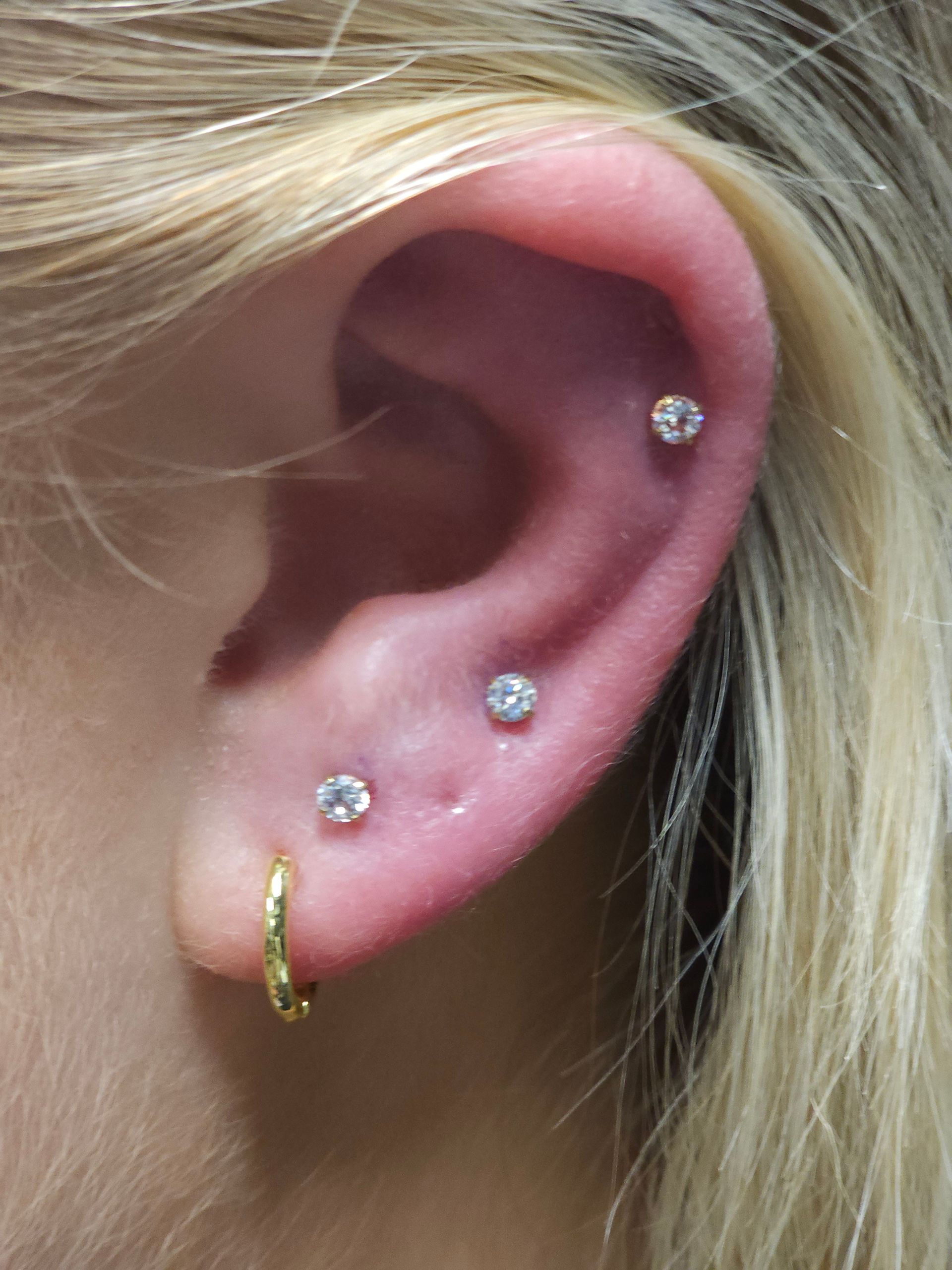 A close up of a woman 's ear with three piercings