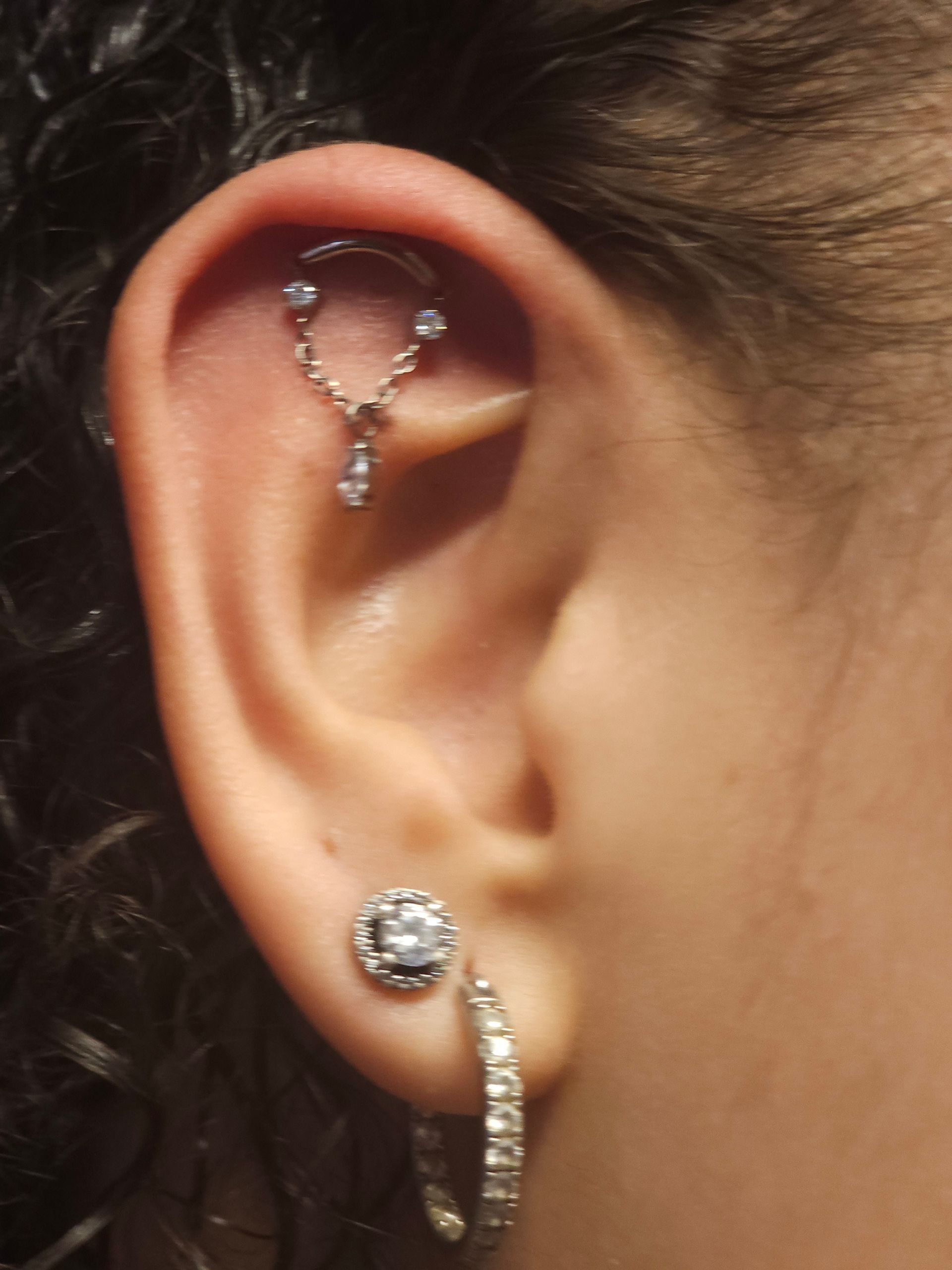 A close up of a woman 's ear with multiple piercings