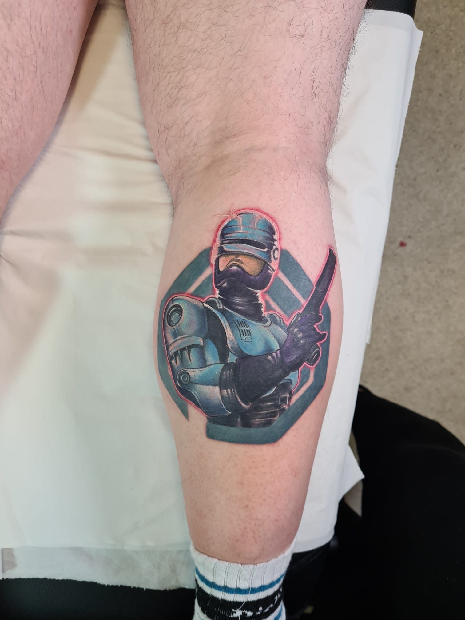 A man has a tattoo of a police officer on his leg.