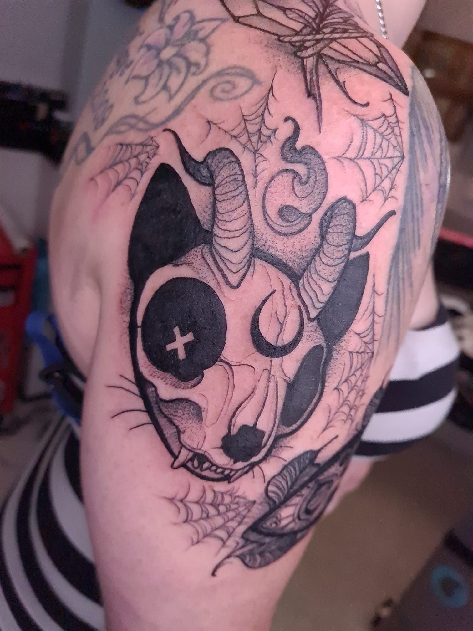 A woman has a tattoo of a cat with horns on her shoulder