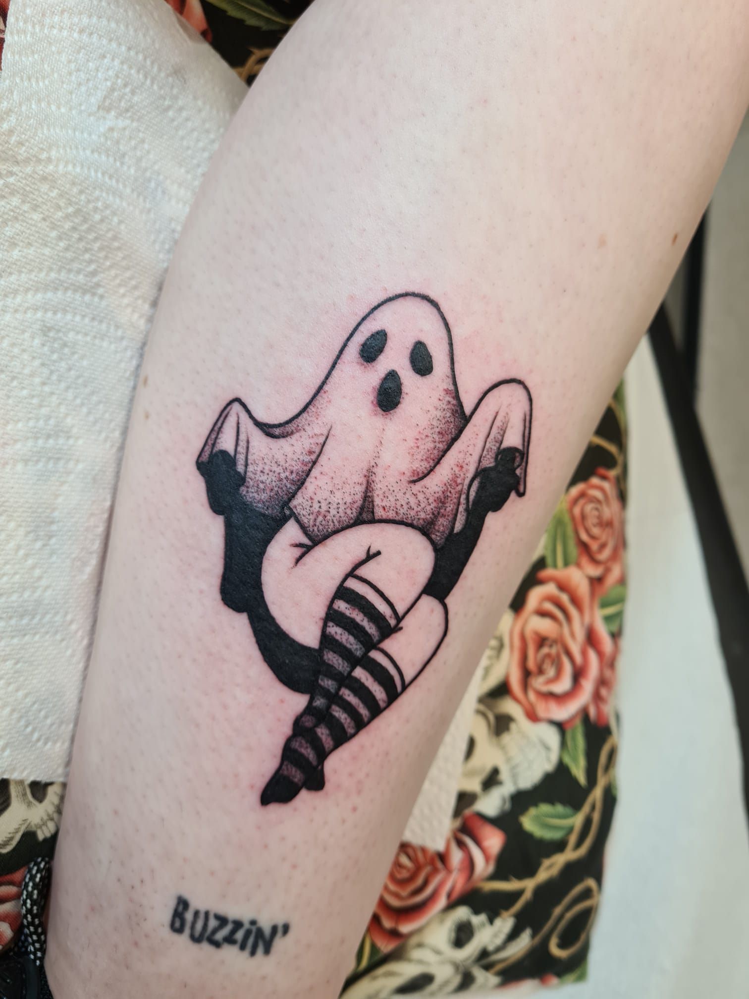 A woman has a tattoo of a ghost with striped socks on her leg.