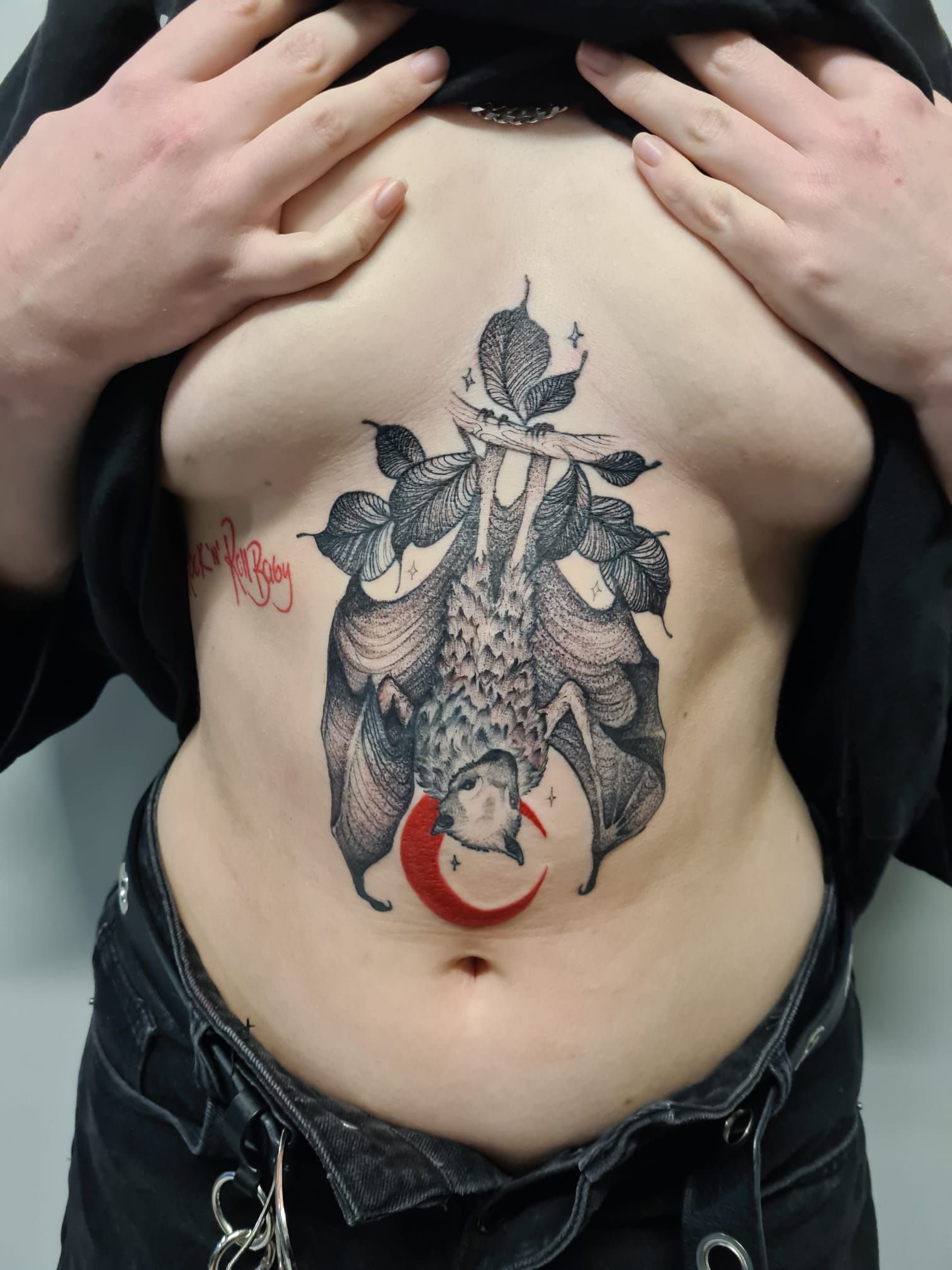 A woman has a tattoo of a bat on her stomach.
