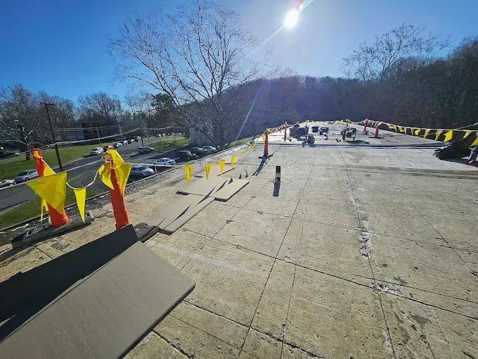 Construction site on a sloped road with orange and yellow markers, a sunny day.