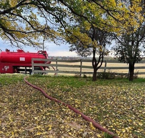 A Red Vacuum Septic Tank Truck is Parked in a Field — Lubbock, TX — Berryhill Sewer Inc.