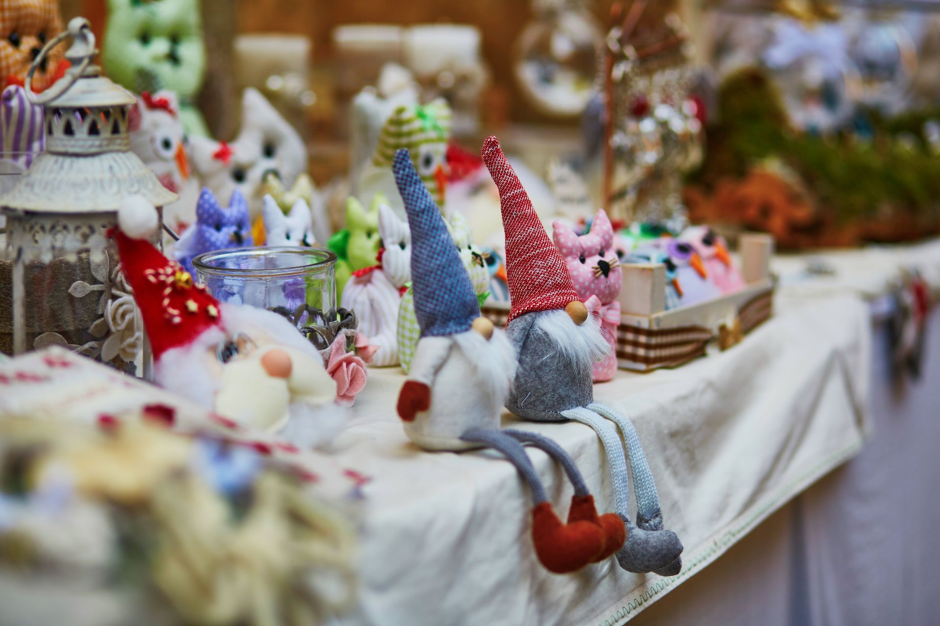 Colorful knitted gnome figurines displayed on a white table at an outdoor market stall