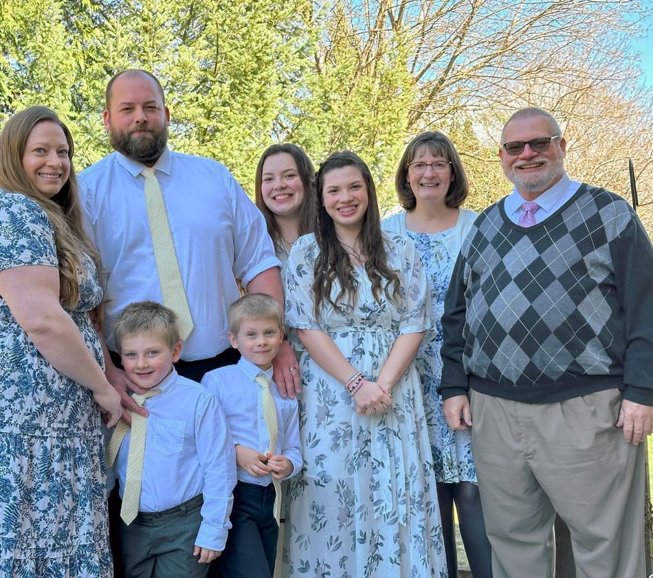 Family group posing outdoors in spring, wearing coordinated light blue and gray outfits.