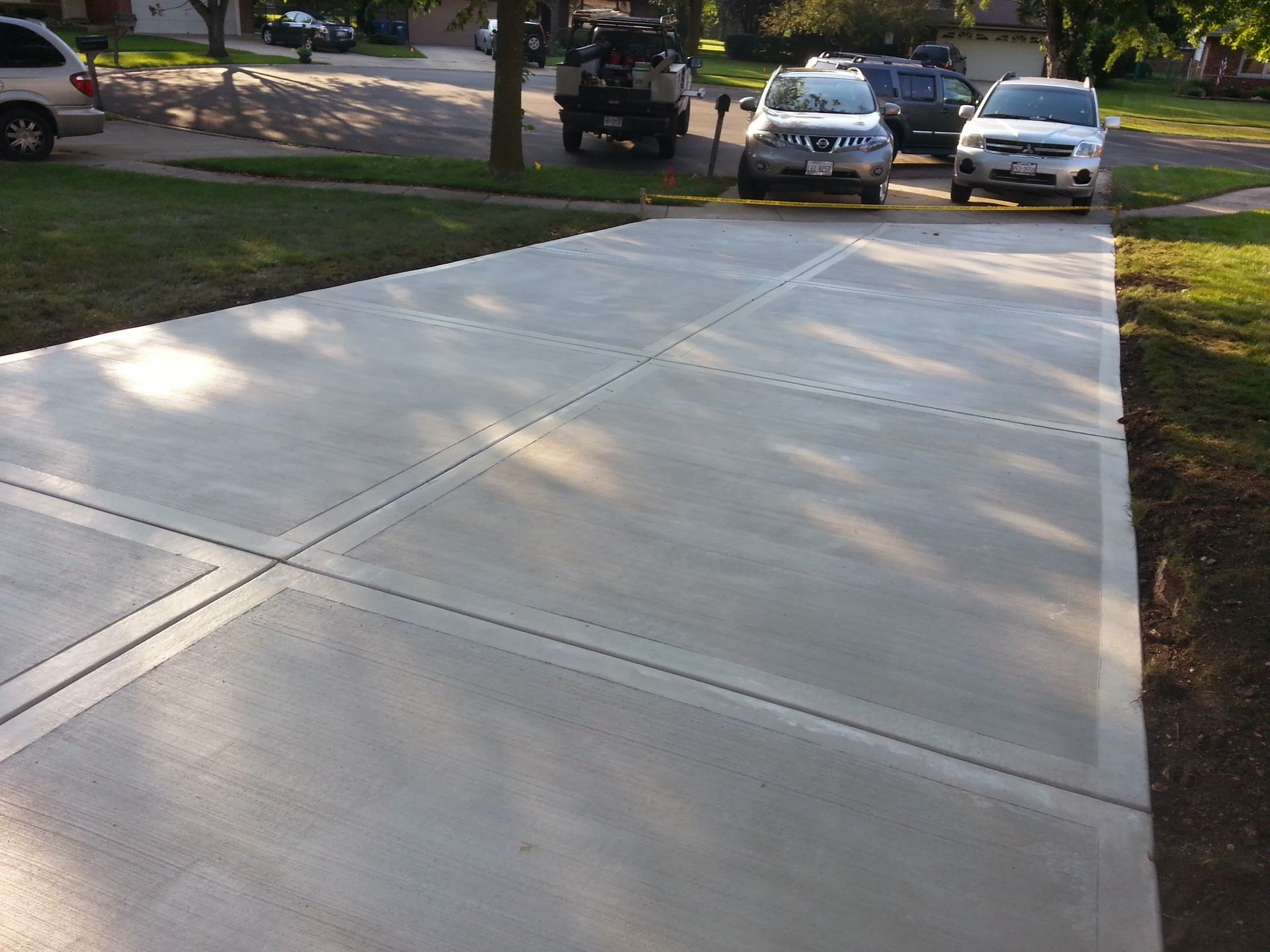 A concrete driveway with cars parked in it