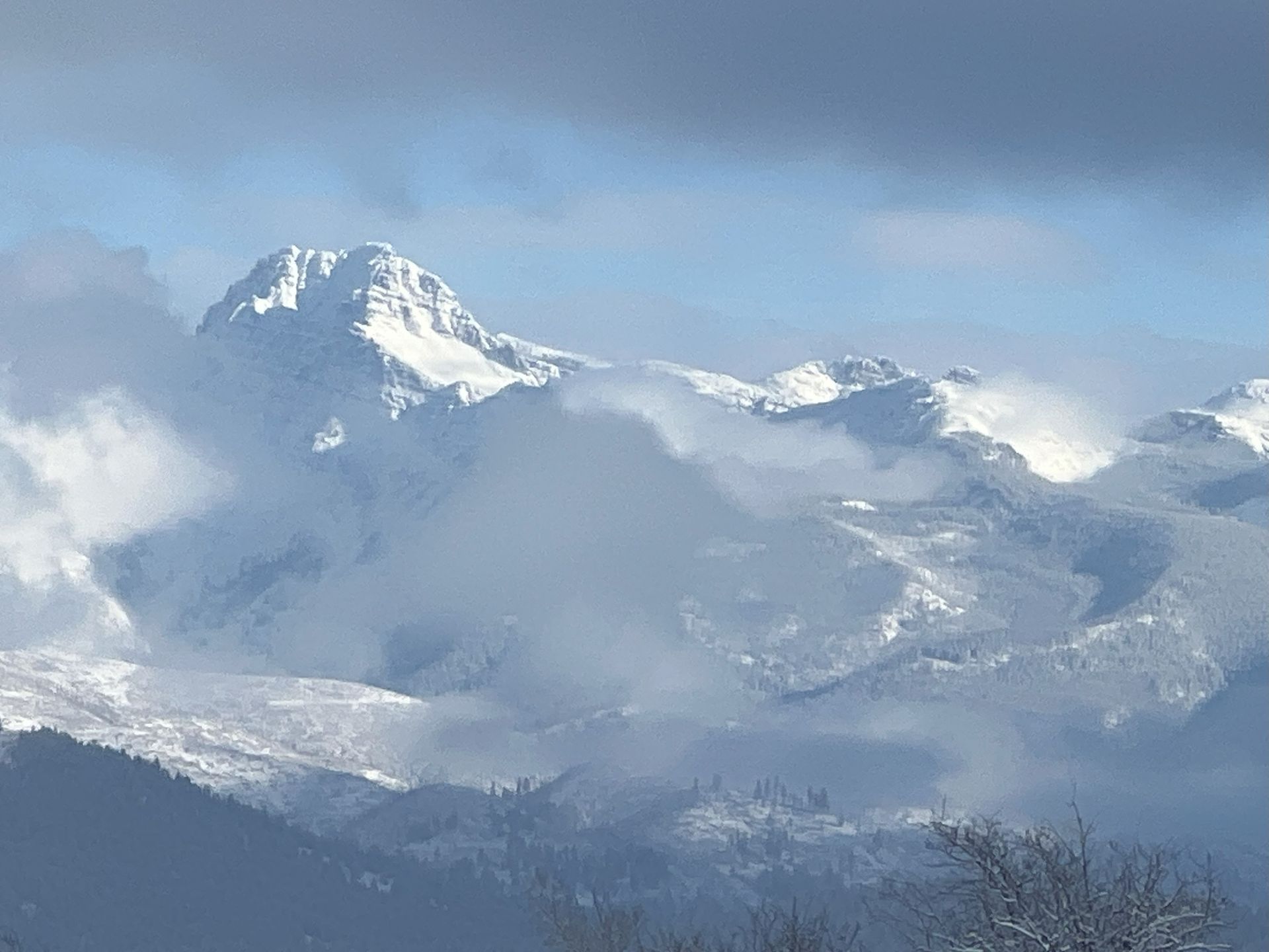 a snowy mountain covered in clouds on a cloudy day