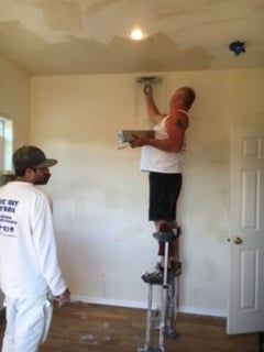 a man standing on a ladder painting a wall