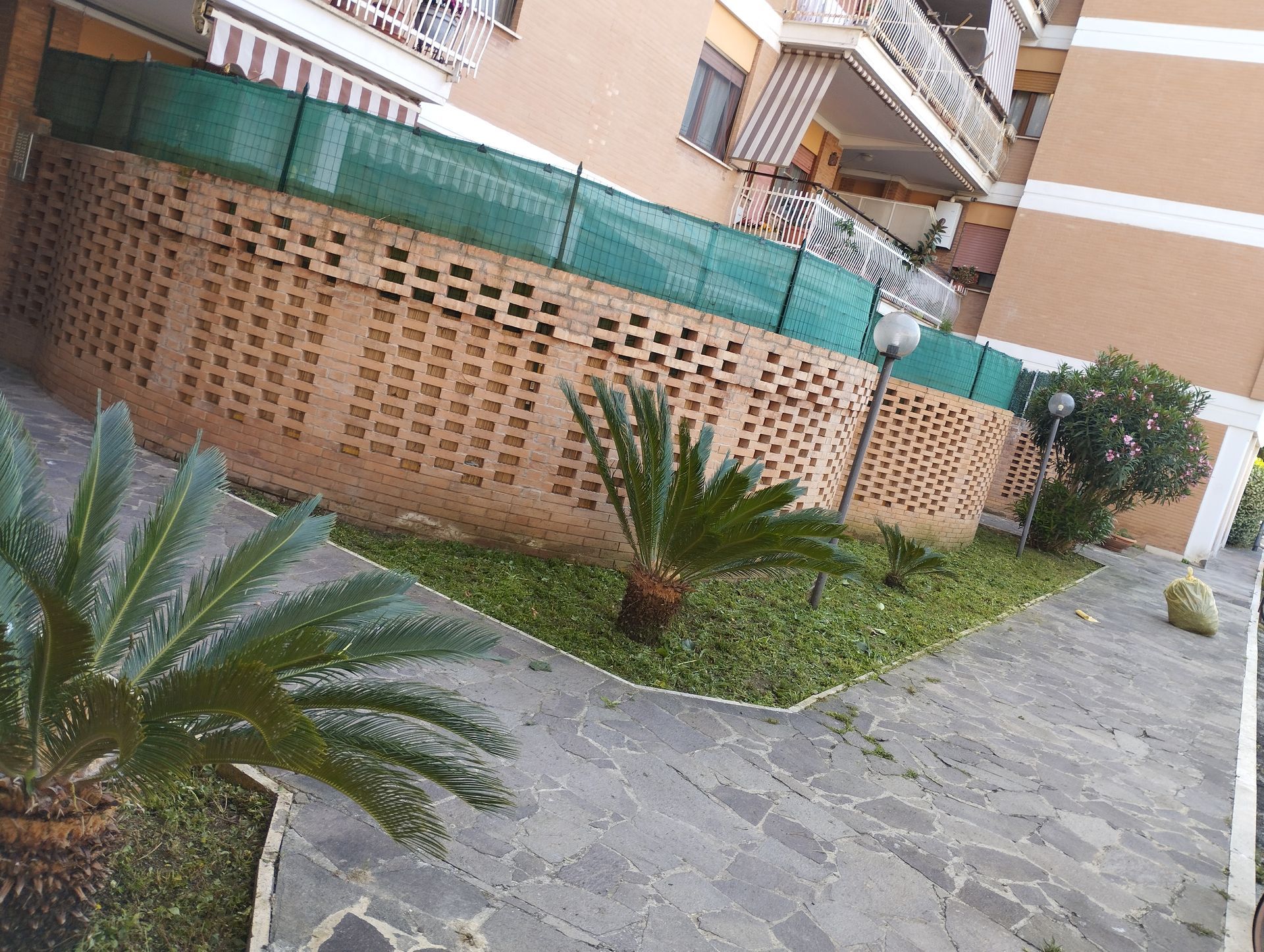 Una recinzione circonda un rigoglioso giardino verde di fronte a un edificio.