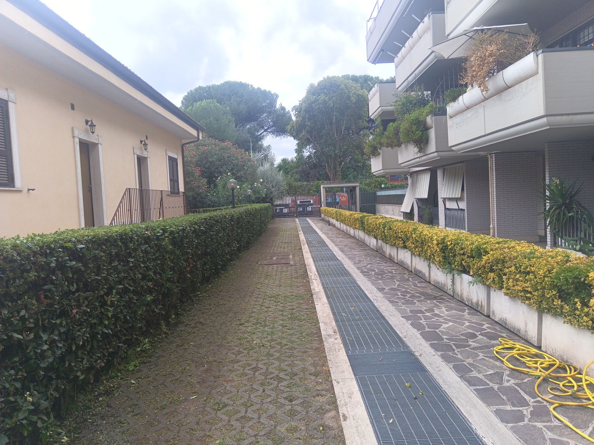 Uno stretto sentiero tra due edifici con un tubo giallo sul marciapiede