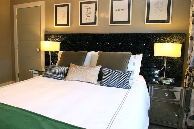 A bedroom with a bed , nightstands , lamps , and pictures on the wall.