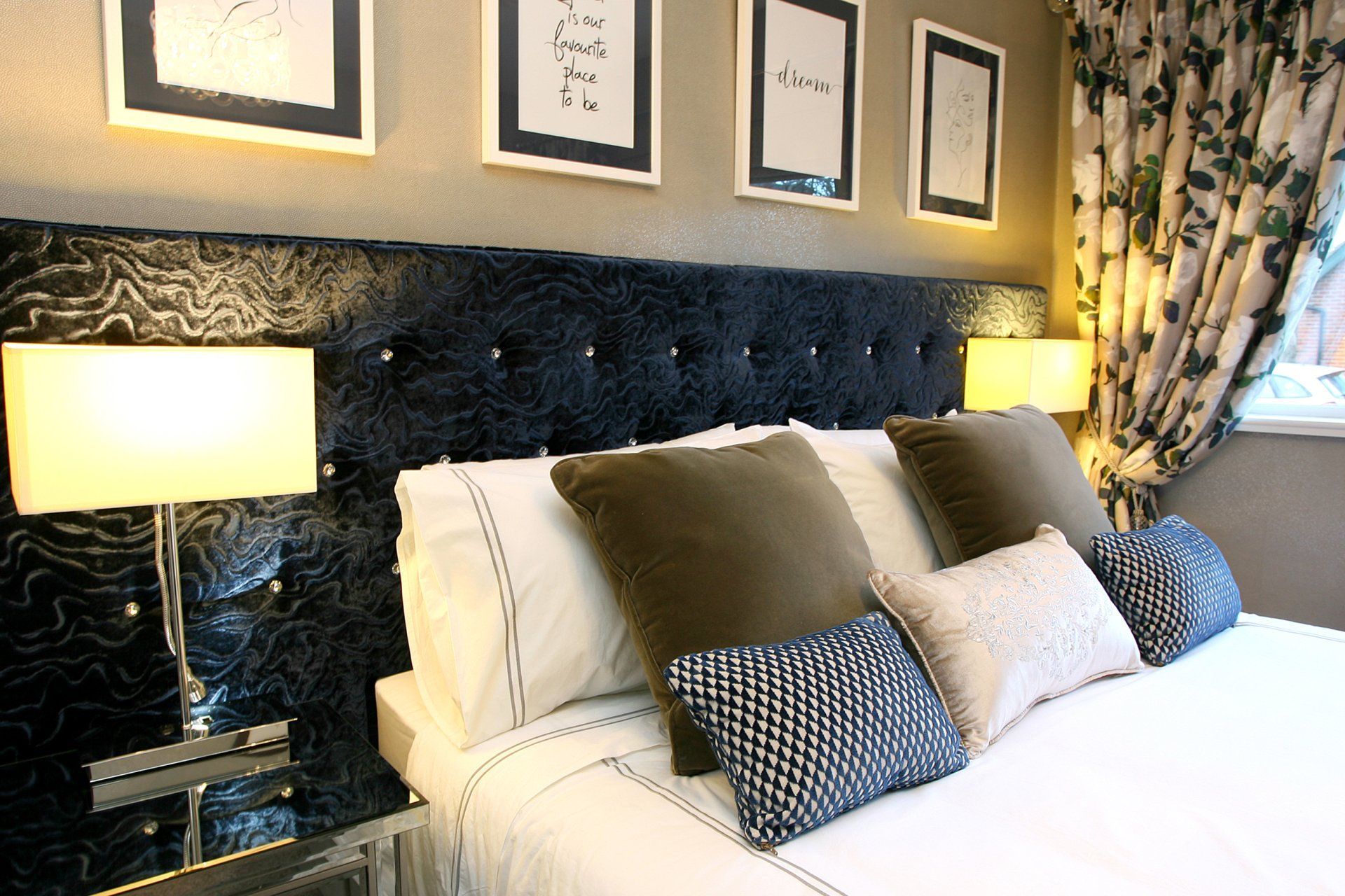 A bedroom with a bed , lamps and pictures on the wall