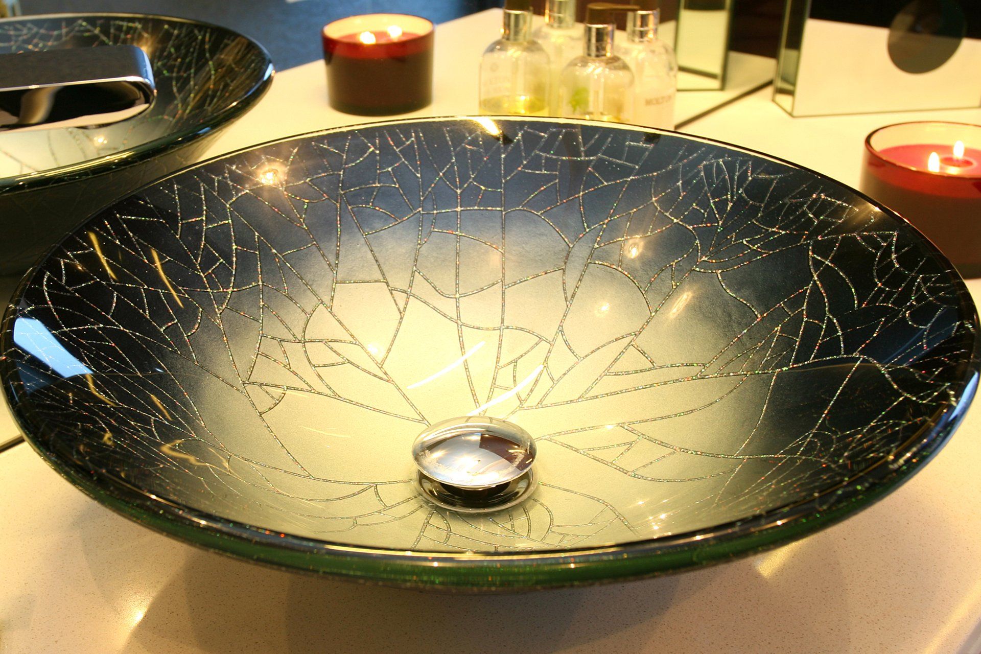 A bathroom sink with candles and bottles in the background