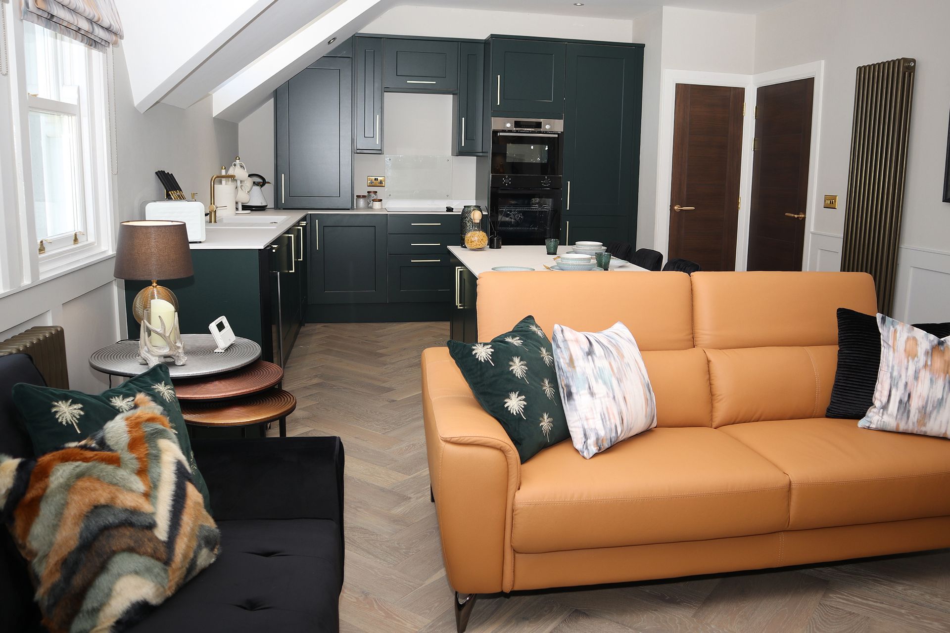 A living room with a couch and a kitchen in the background.