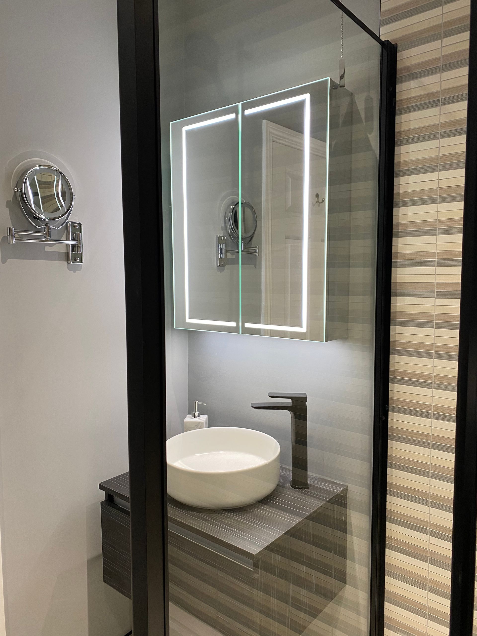 A bathroom with a sink , mirror and shower stall.